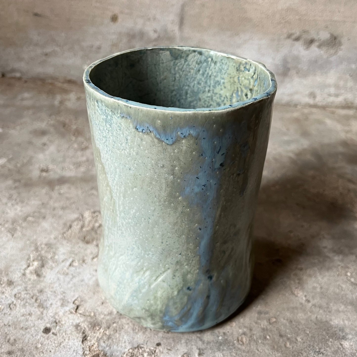 Green ceramic vase on a textured stone surface
