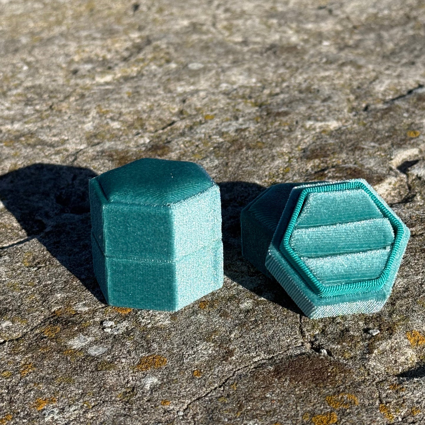 Teal geometric jewelry box on a textured stone surface