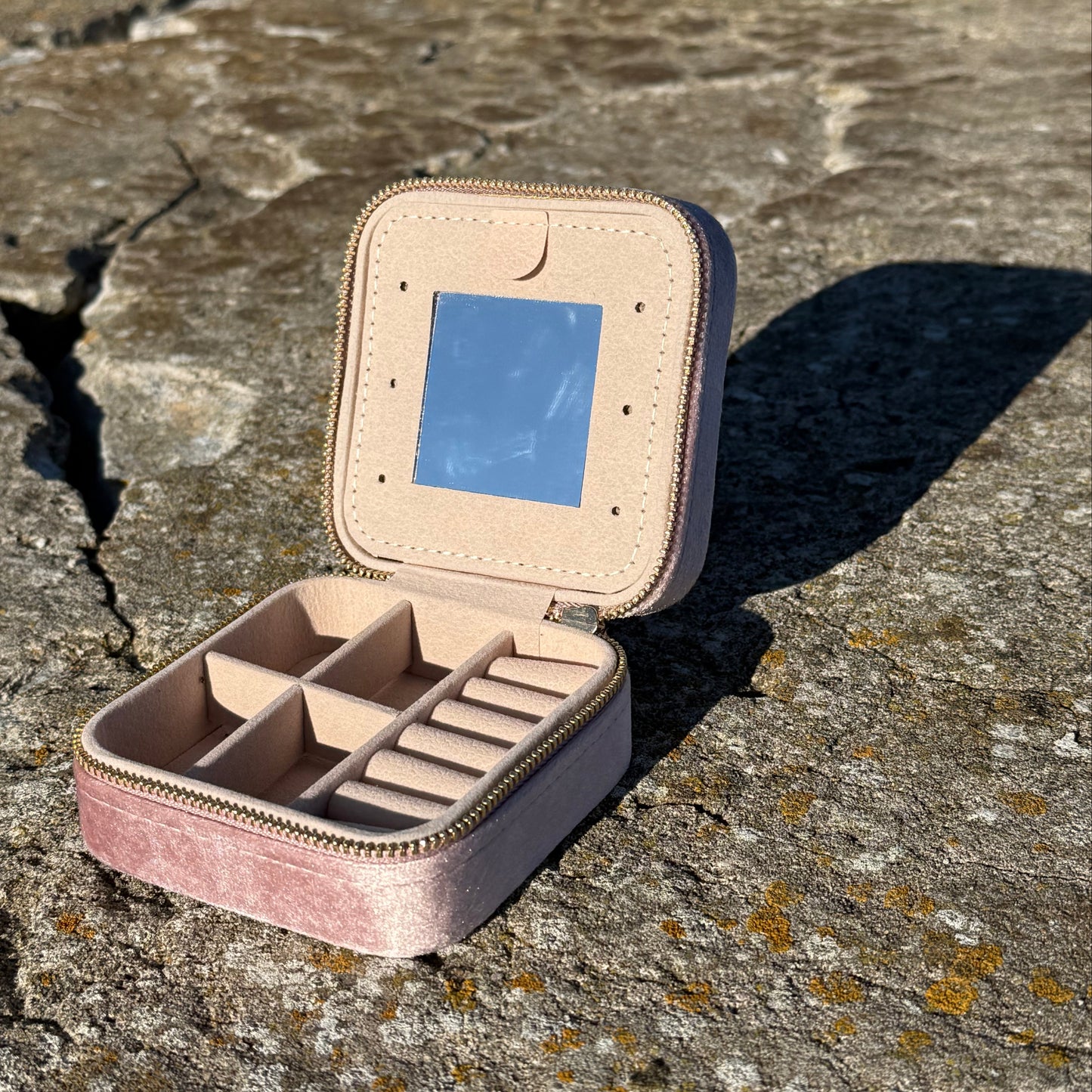 pink jewellery case with mirror on a stone surface