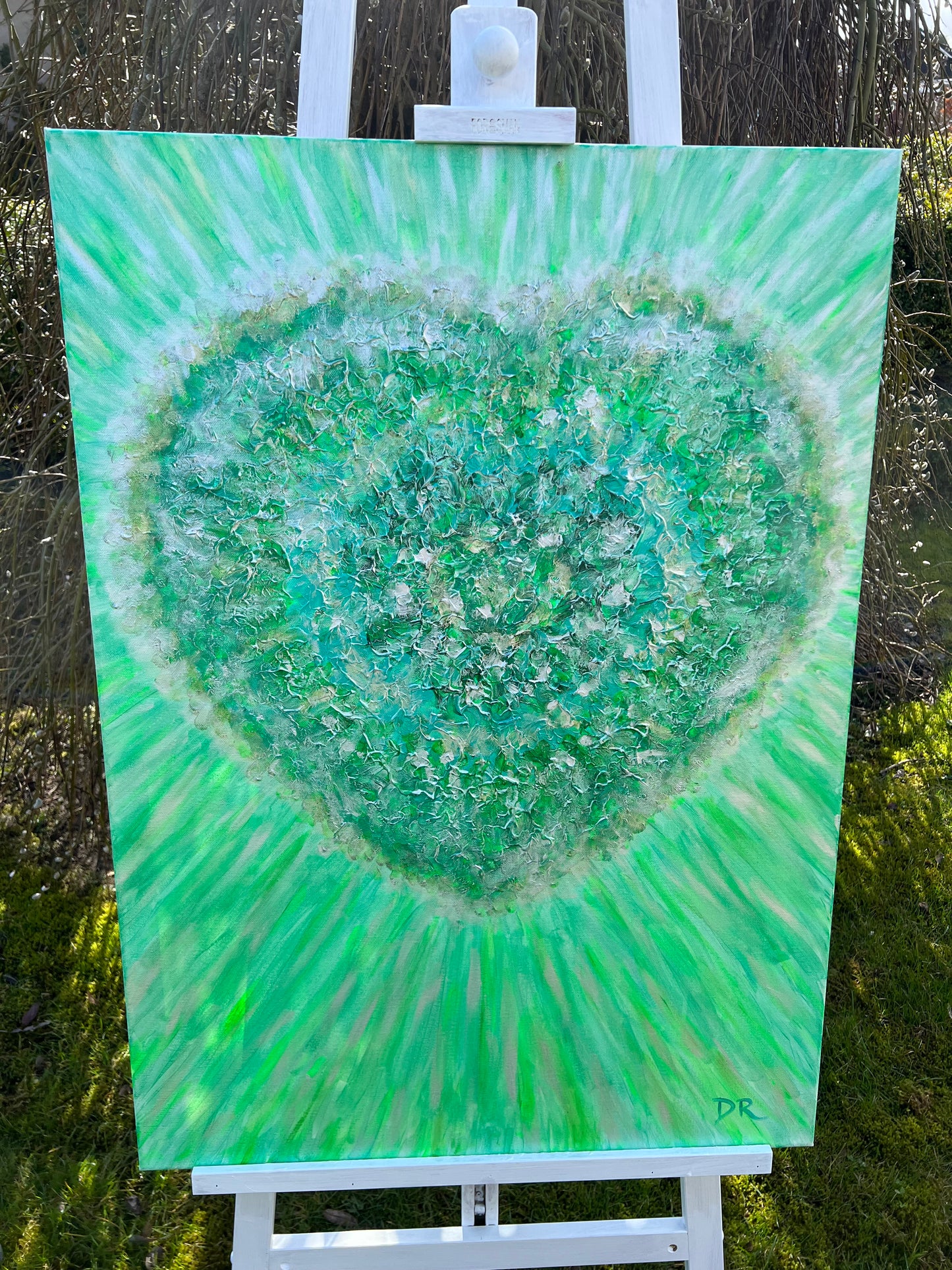 Green abstract painting on a white easel outdoors