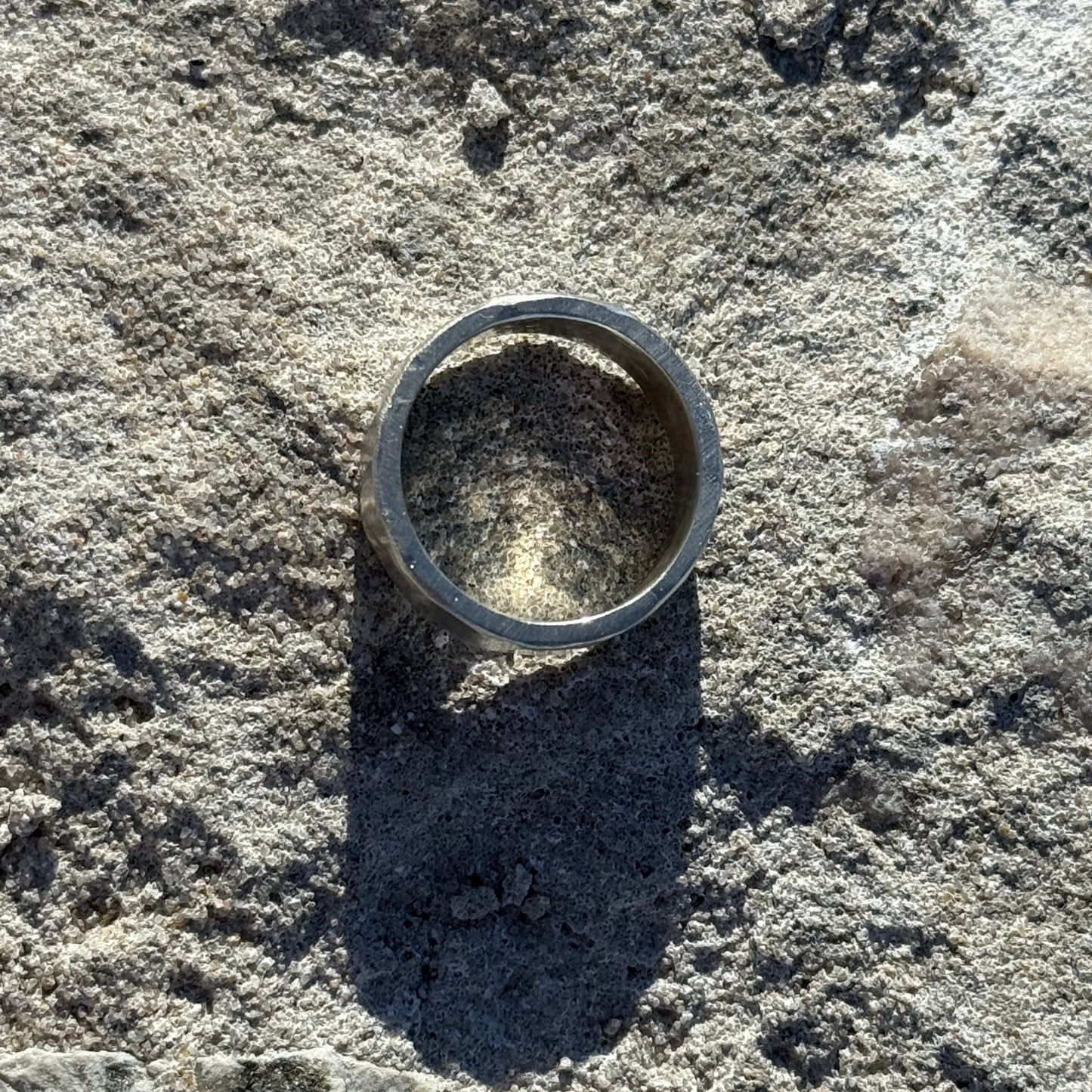 Thick hammered Silver ring on a textured stone surface
