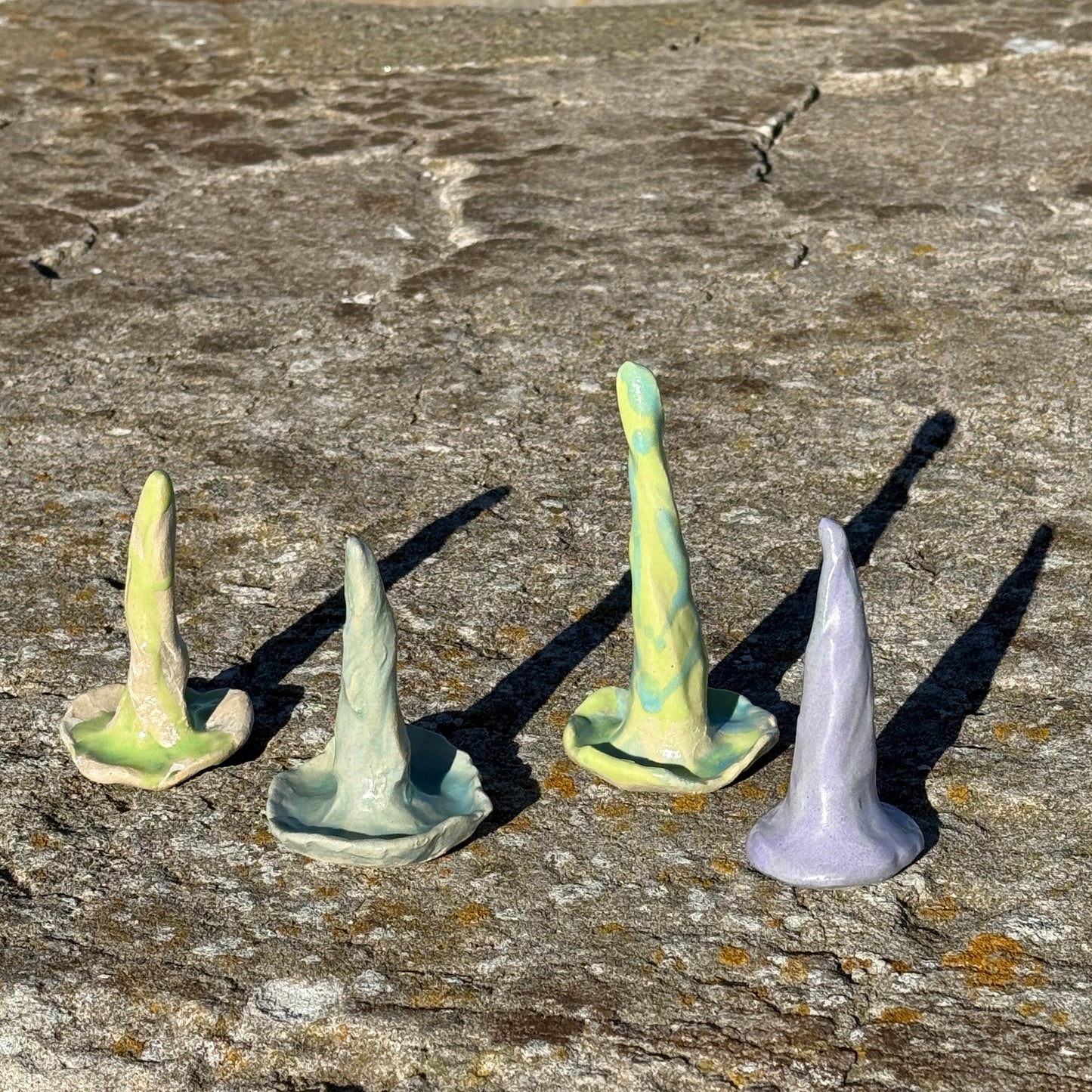 glazed colorful ceramic ring cones and jewelry holders on a textured stone surface