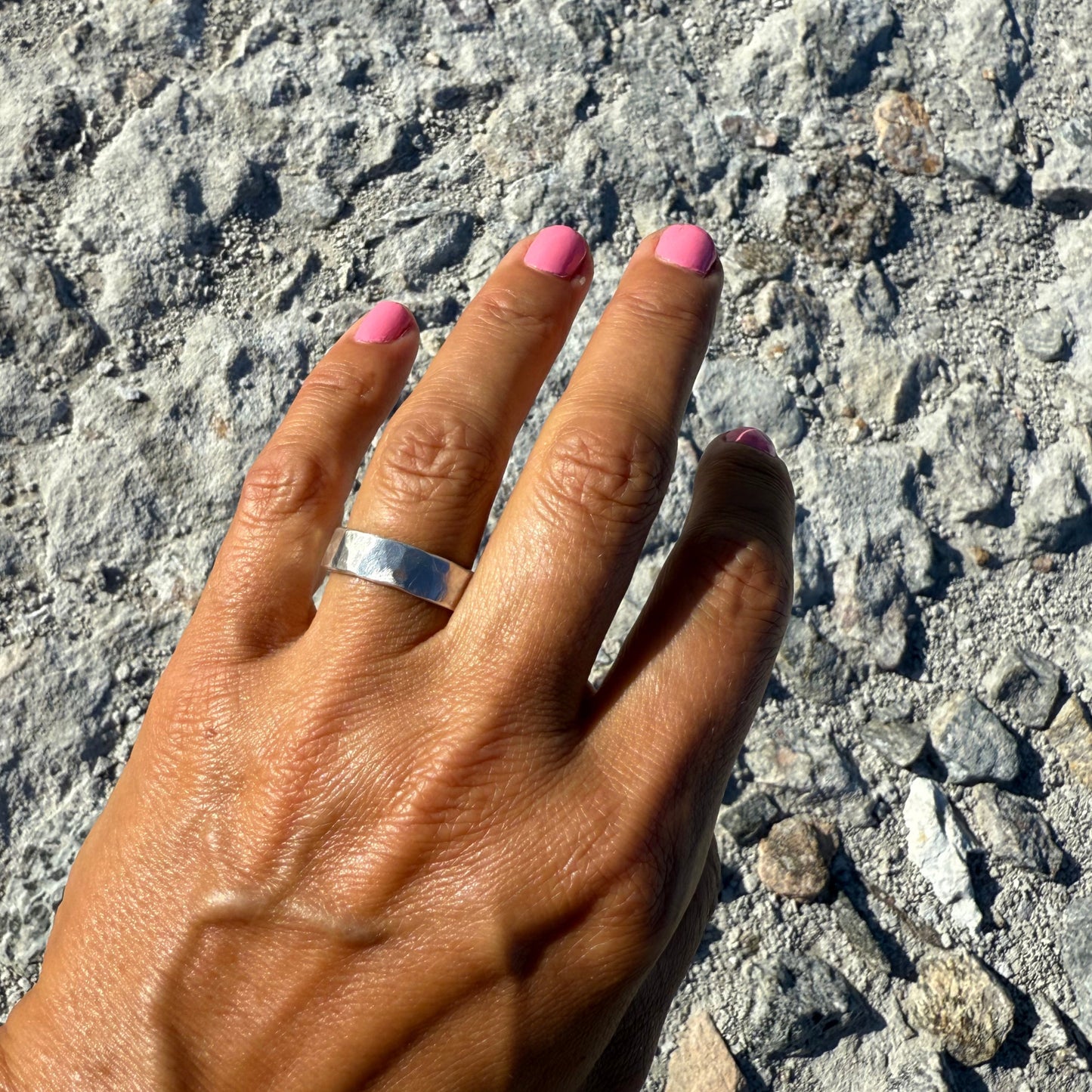 Hand with a sterling silver ring on a textured surface
