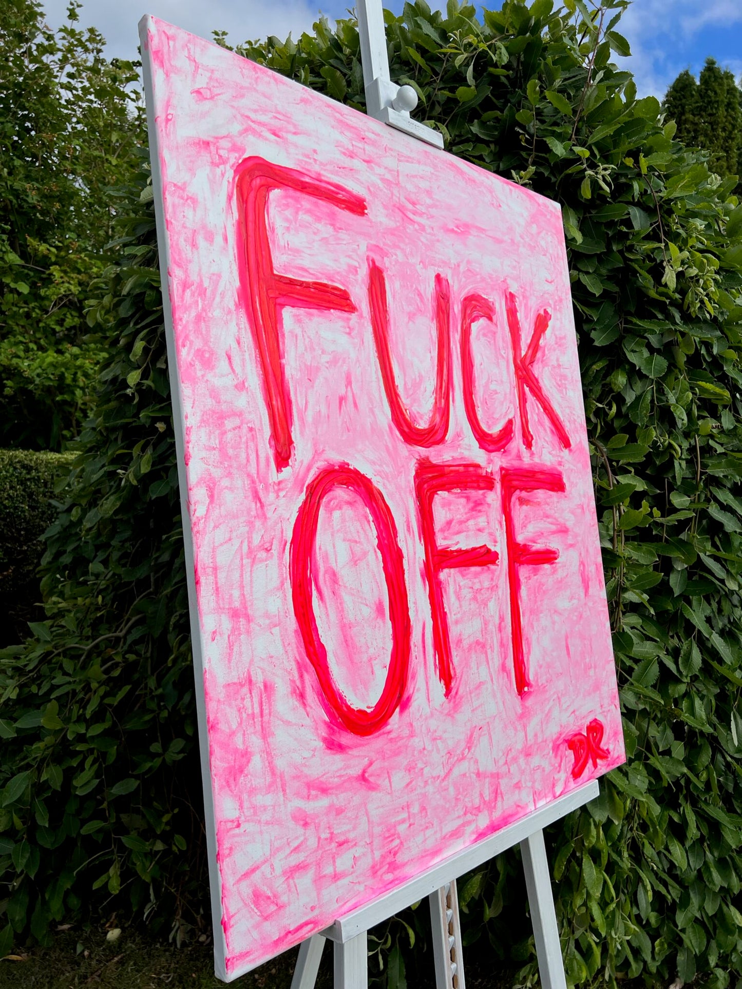 Pink sign with 'FUCK OFF' text on a stand outdoors