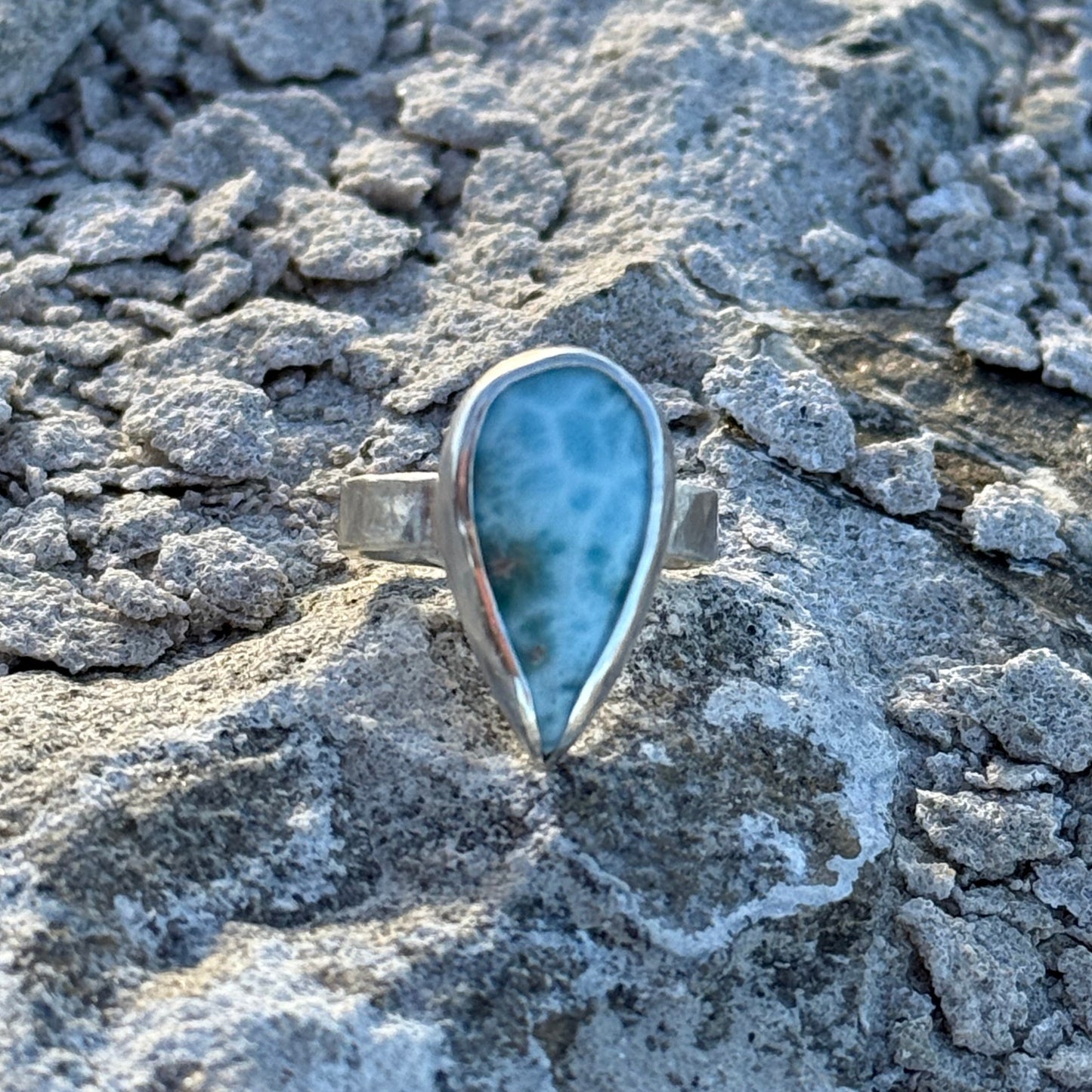 Teardrop-shaped stone ring on a textured stone surface