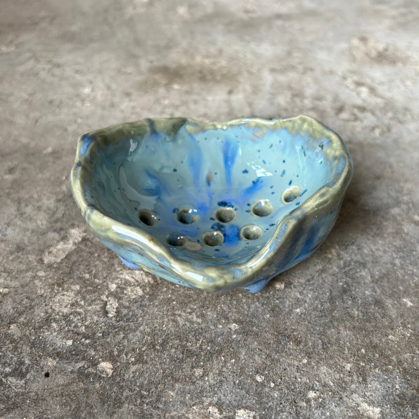 Ceramic soap dish with blue glaze on a concrete surface