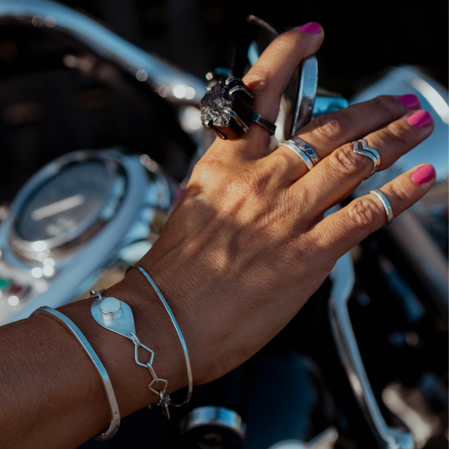 Hand with atelier Desirée handmade jewelry on a Kawasaki motorcycle handlebar