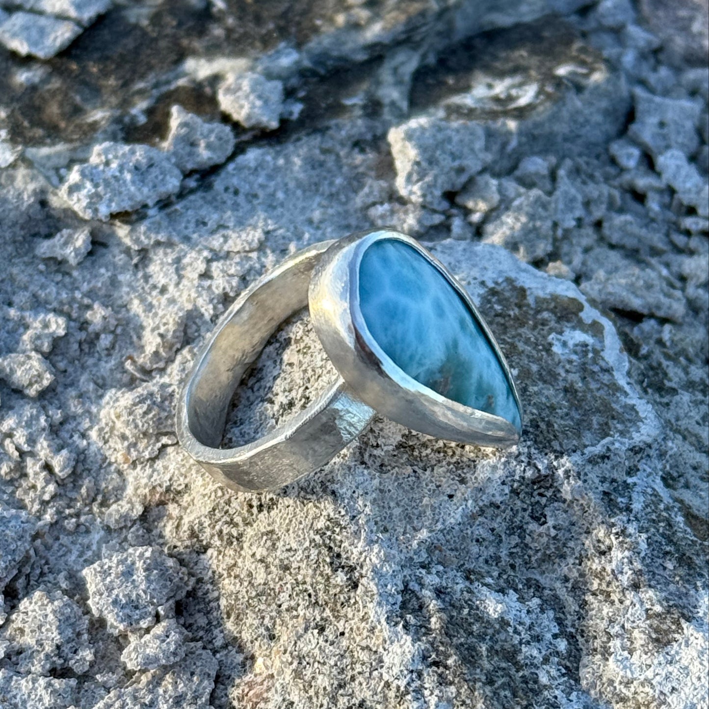 Silver ring with a blue stone on a textured gray surface