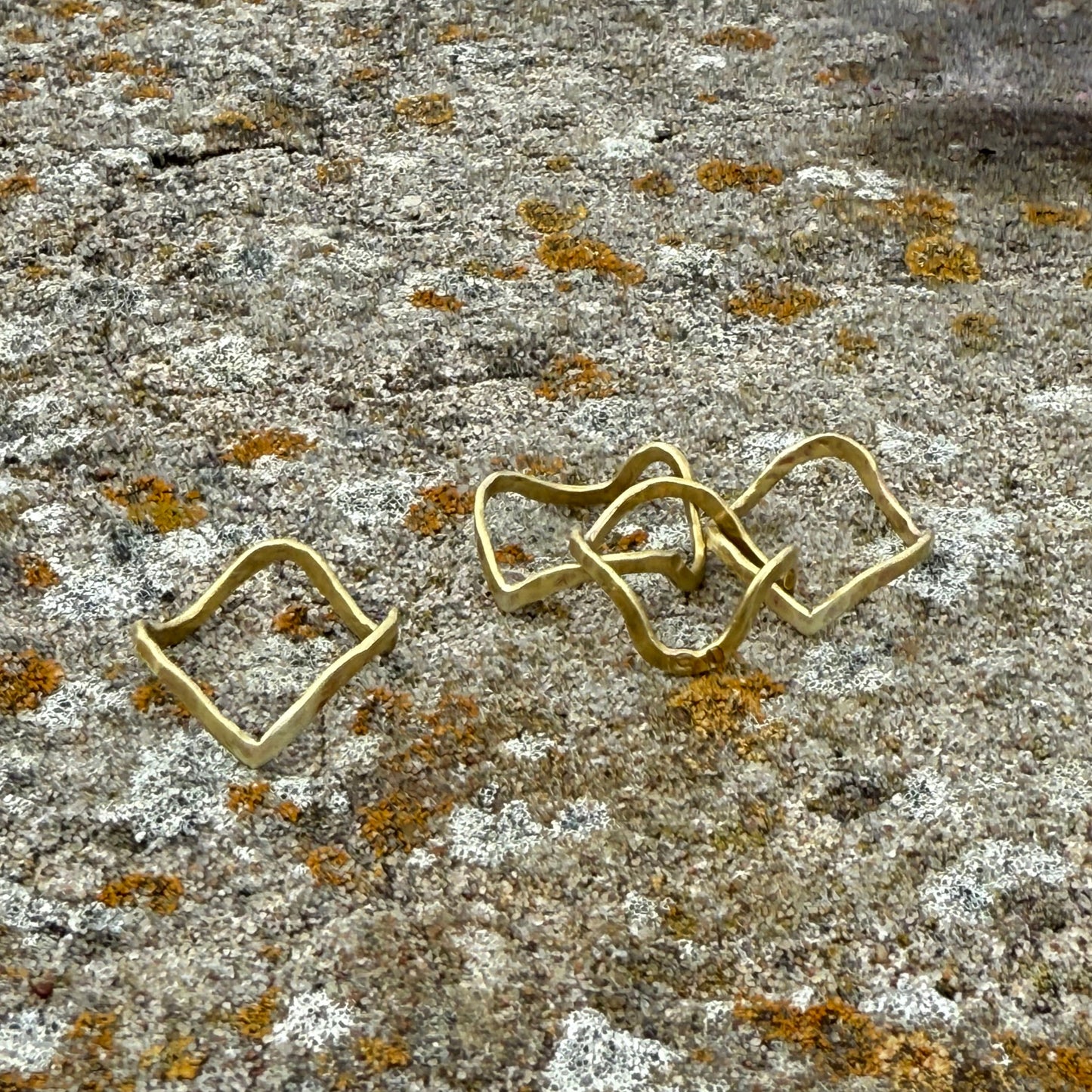 brass wave rings on a textured stone surface