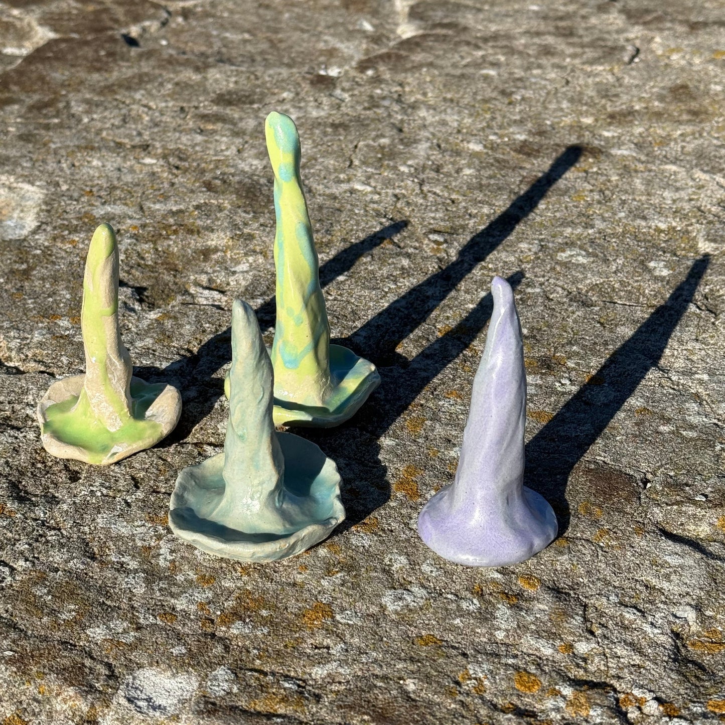 ceramic ring cones in lime green, purple and soft teal on a pier by the ocean