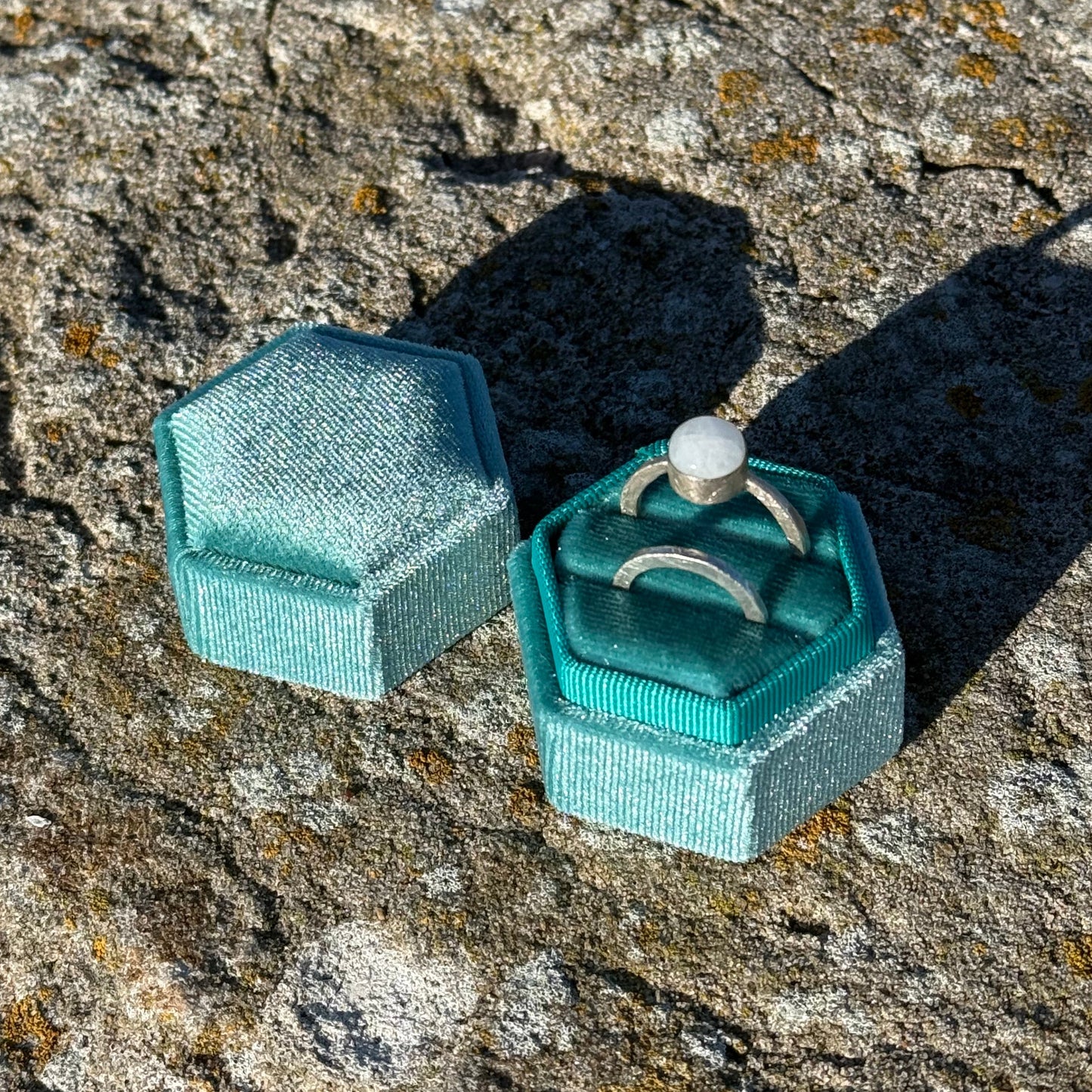 Turquoise ring box with two rings on a textured stone surface