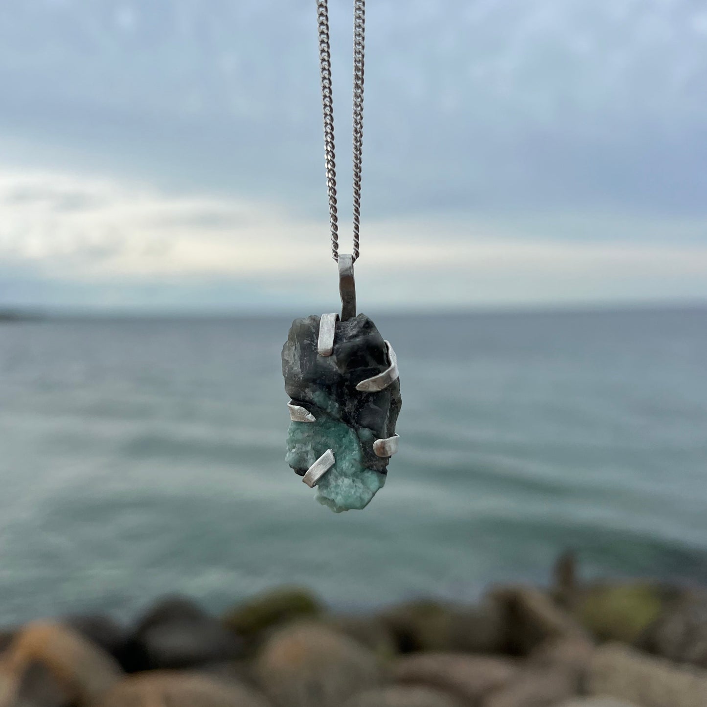 Necklace with emerald silver pendant against a blurred natural background