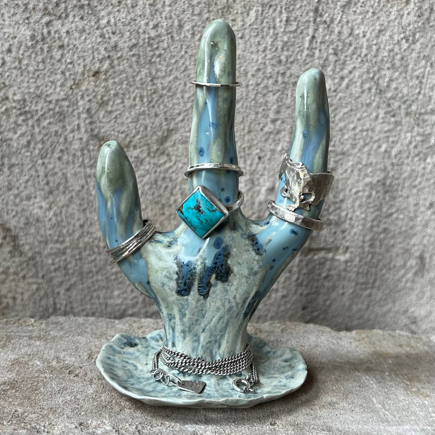 Decorative hand-shaped ring holder with rings on a textured surface