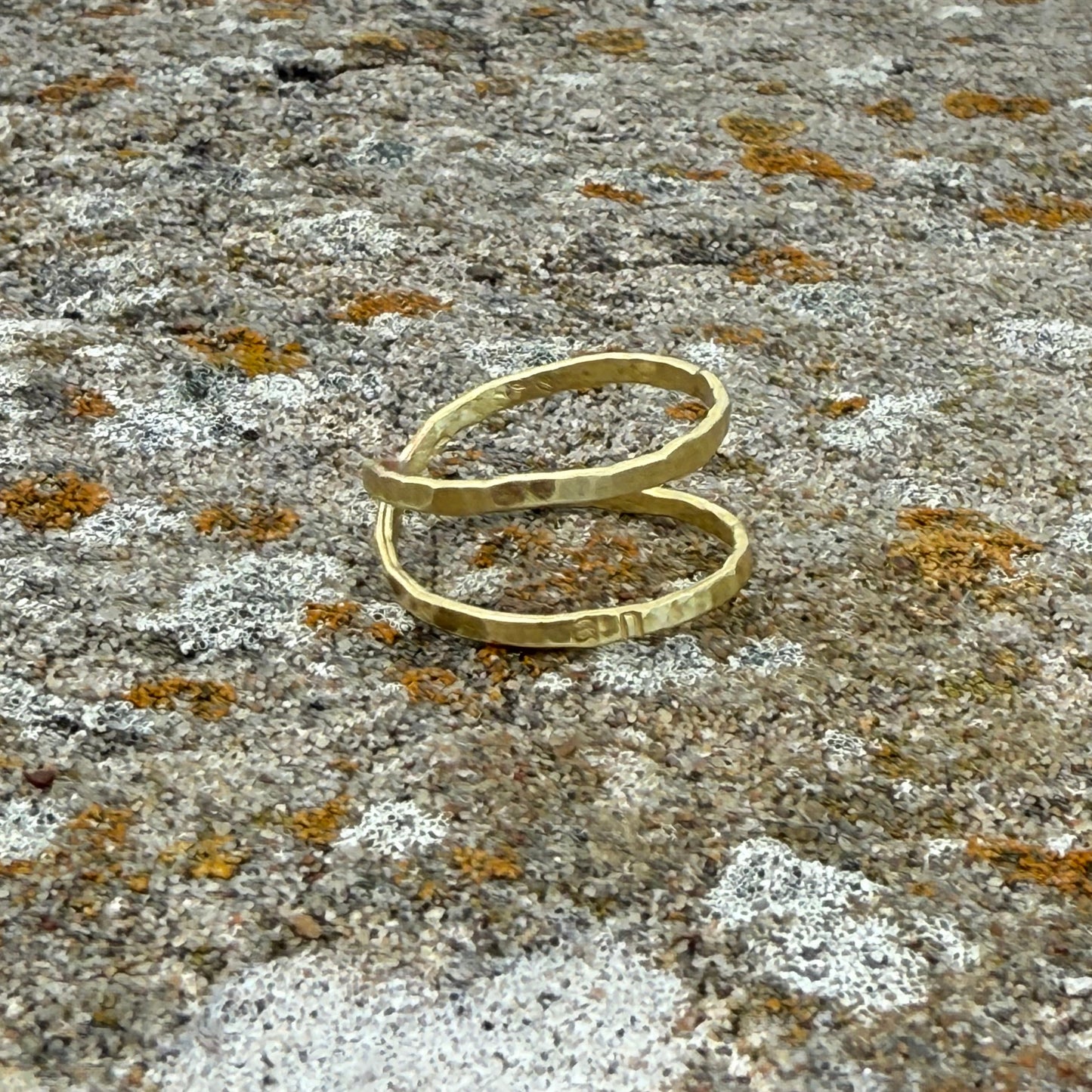 brass infinity ring on a textured stone surface