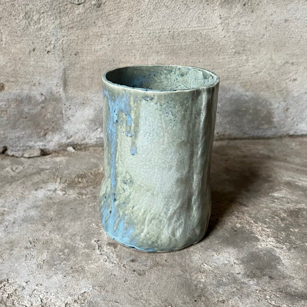 Handmade ceramics vase on a concrete floor with a gray wall background