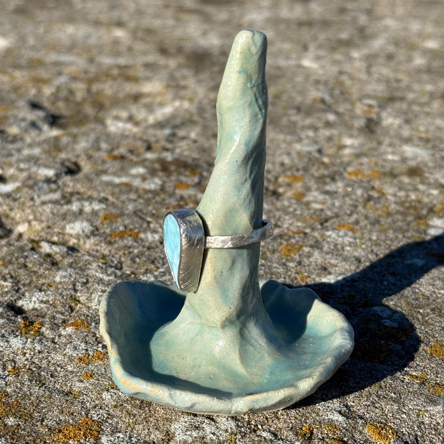 Clay ring cone holding a larimar silver ring on a textured stone surface