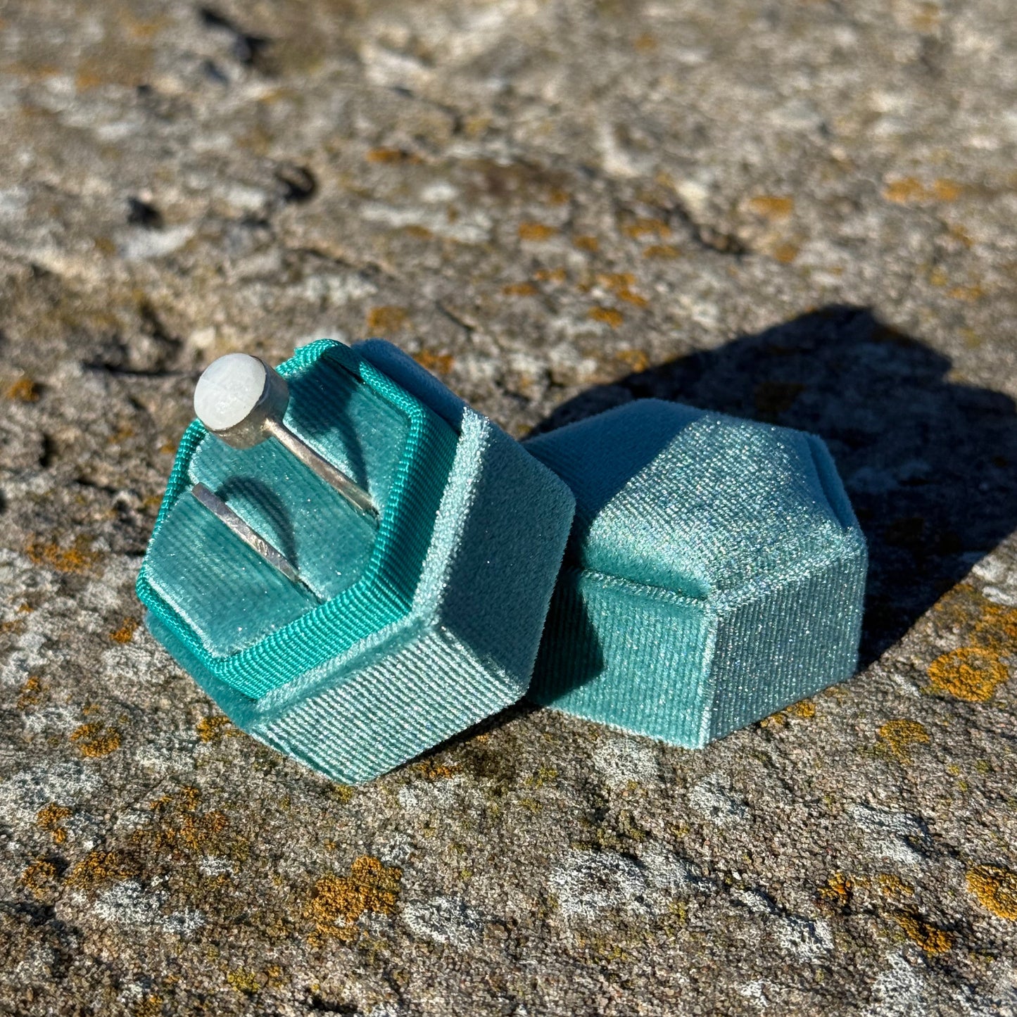 teal gloves velvet jewelry box on stone surface