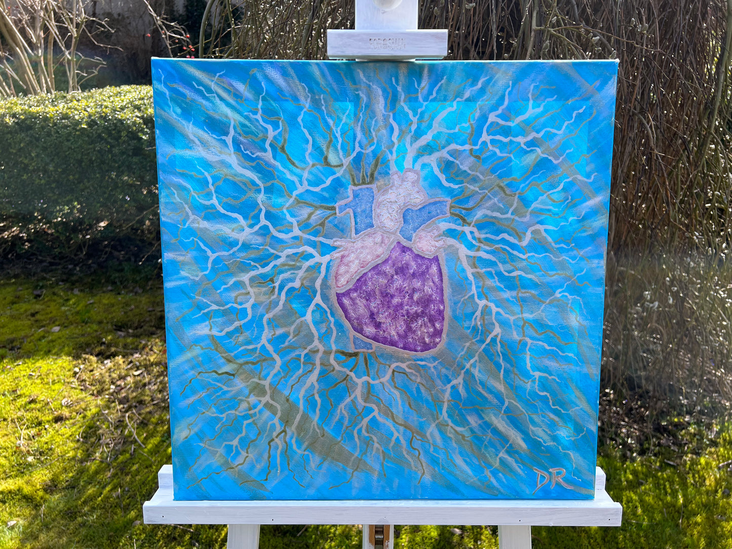 Painting of a stylized heart on a blue background, displayed on an easel outdoors.