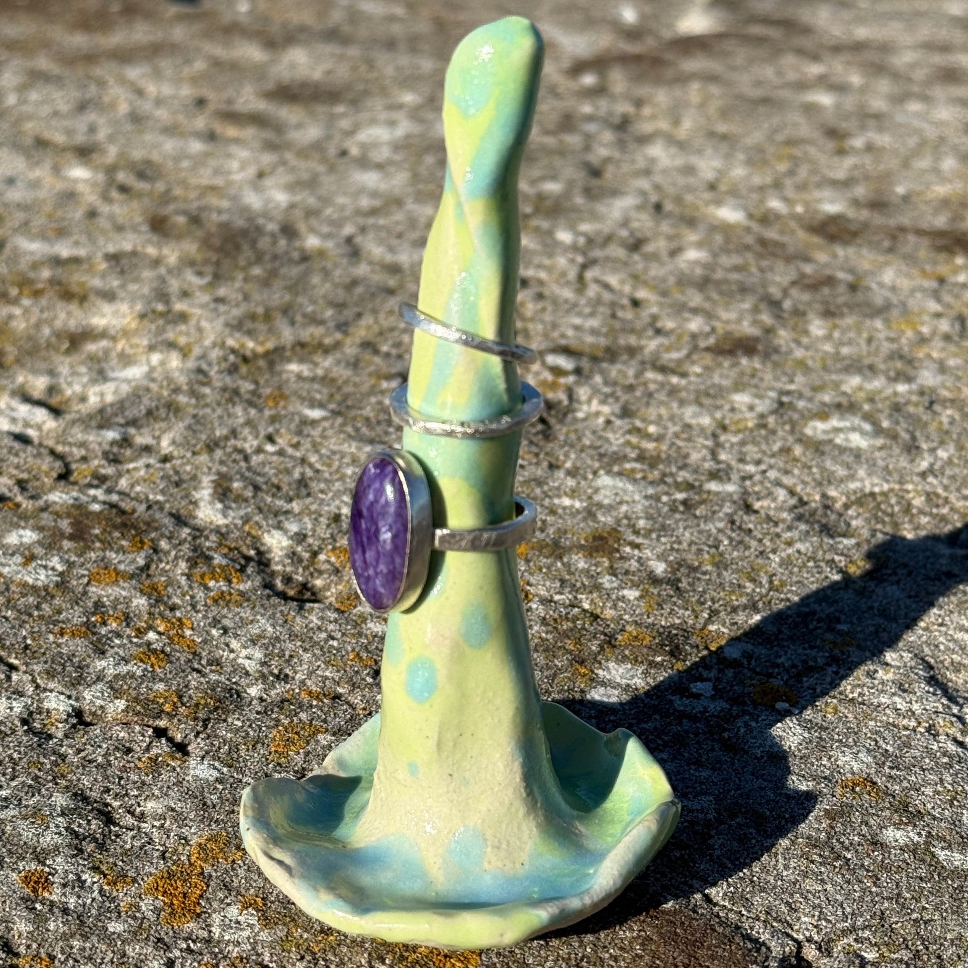 ceramic ringholder in lime green and turquoise with silver rings stacked on top 