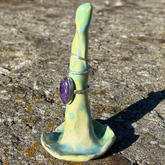 ceramic ringholder in lime green and turquoise with silver rings stacked on top 