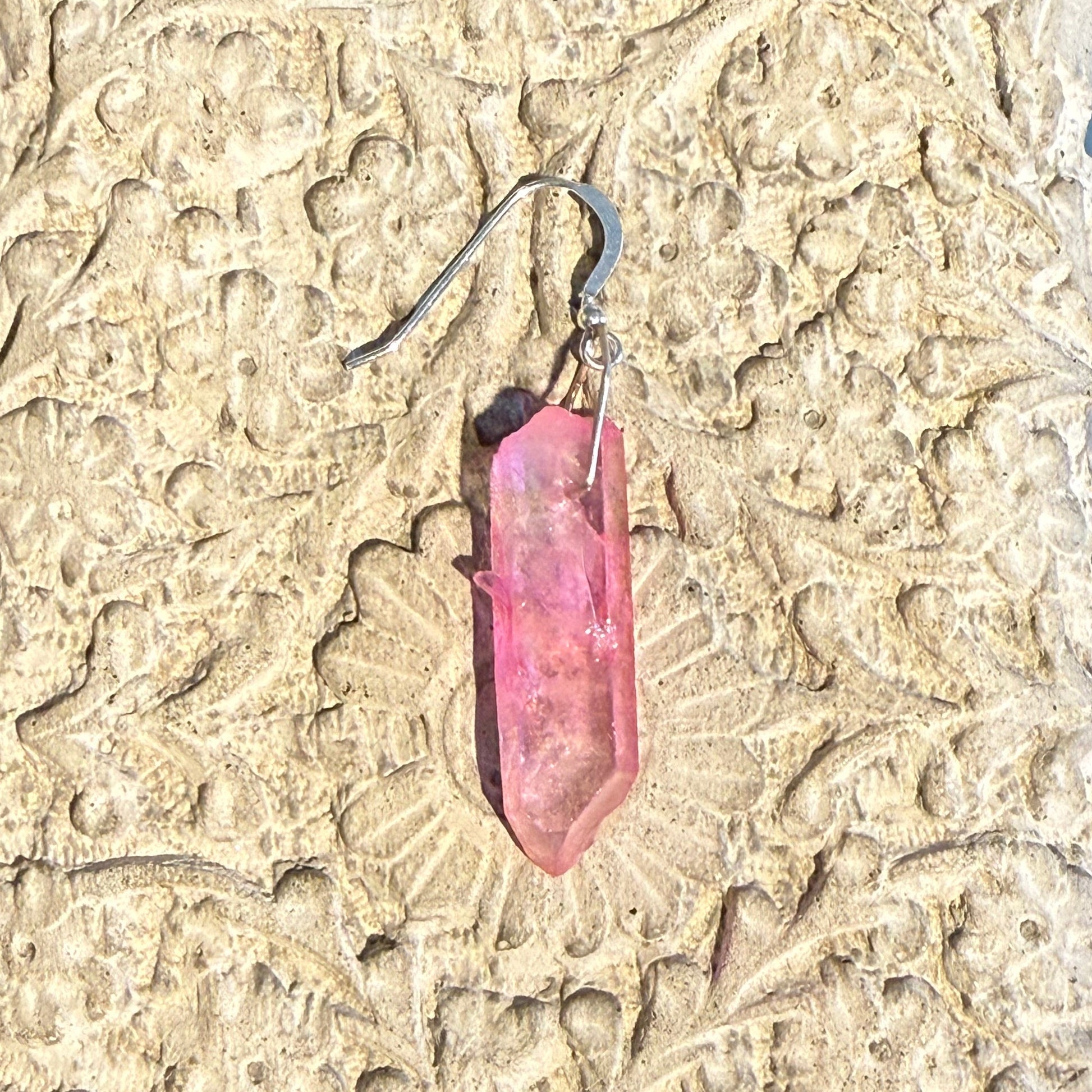 Pink crystal earring on a textured stone surface