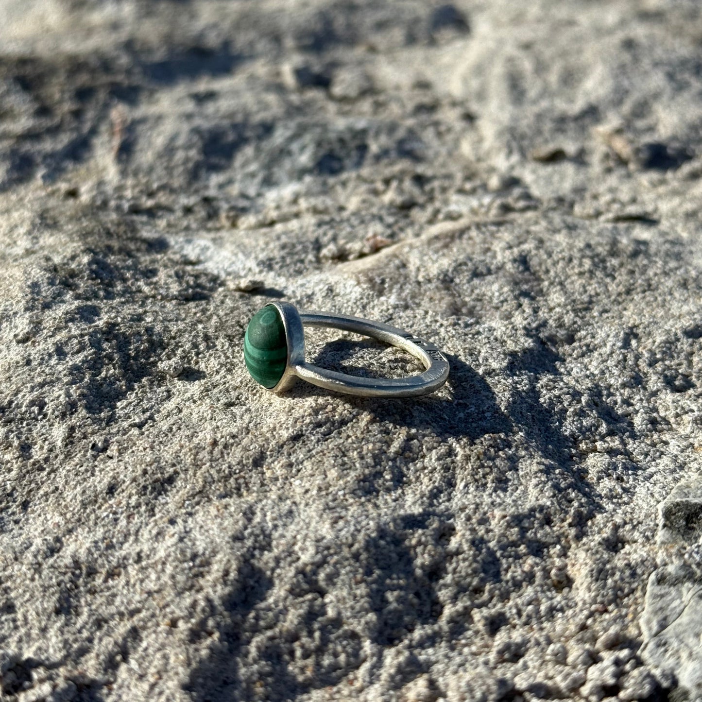 malachite sterling silver ring on a rocky surface