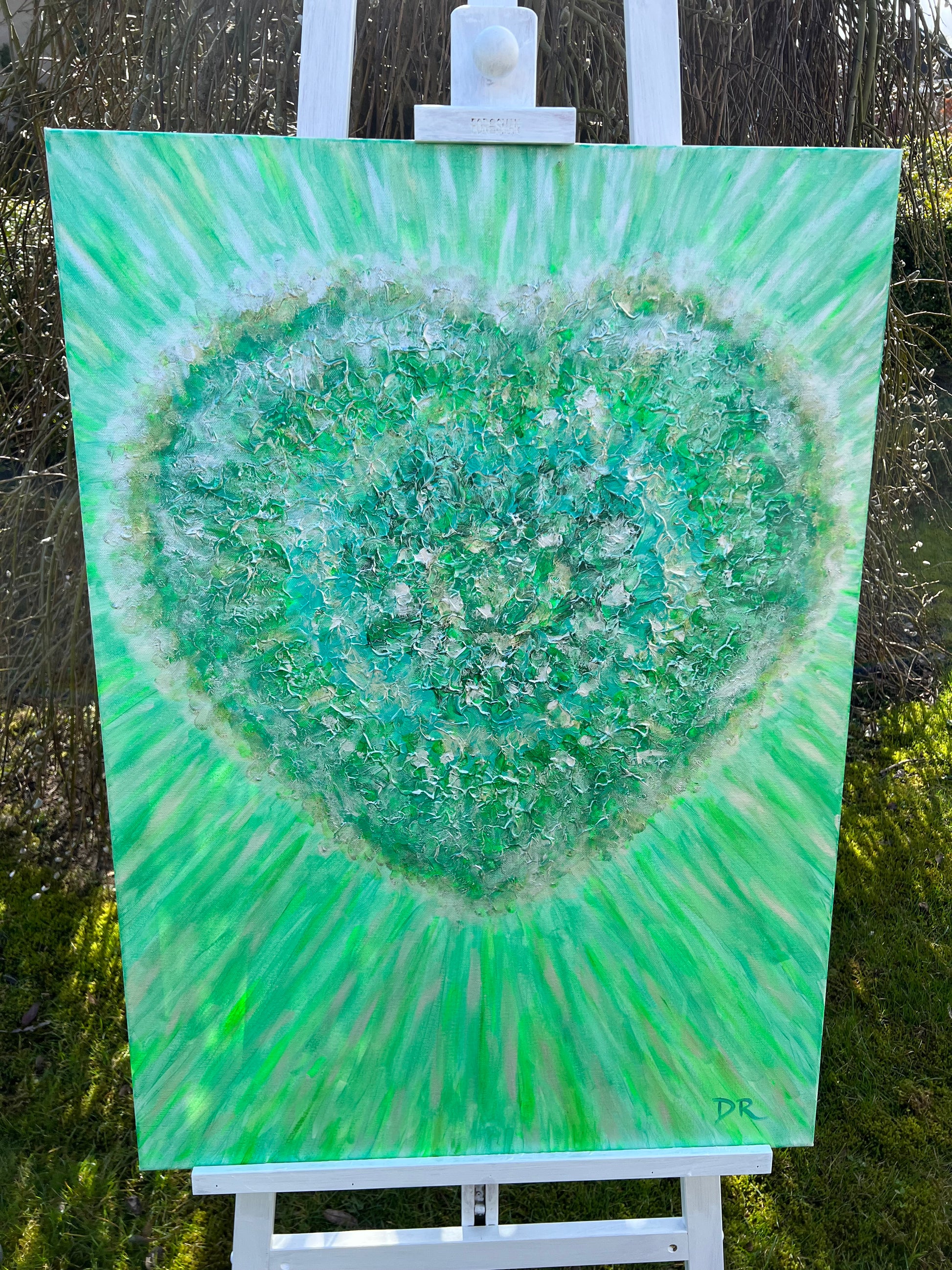 Green abstract painting on a white easel outdoors