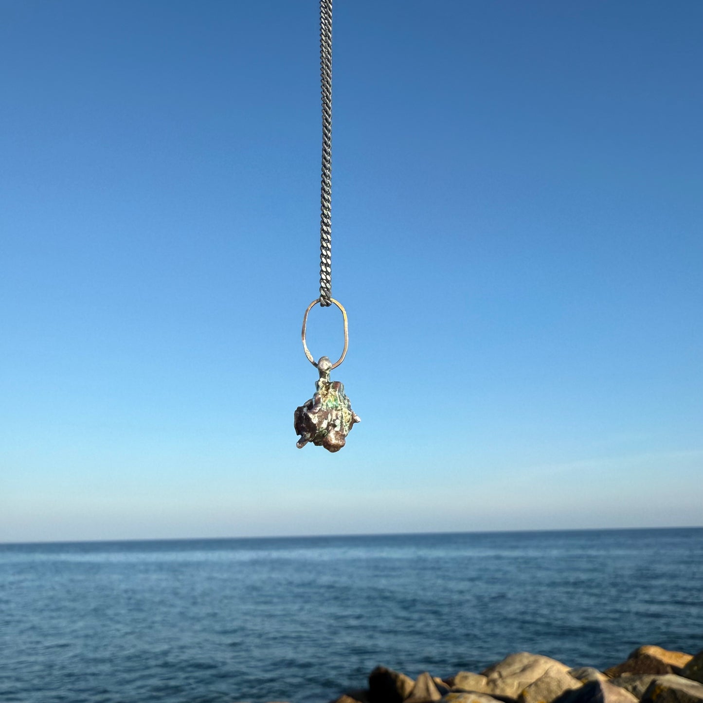 Necklace with a pendant against a blue sky and ocean background