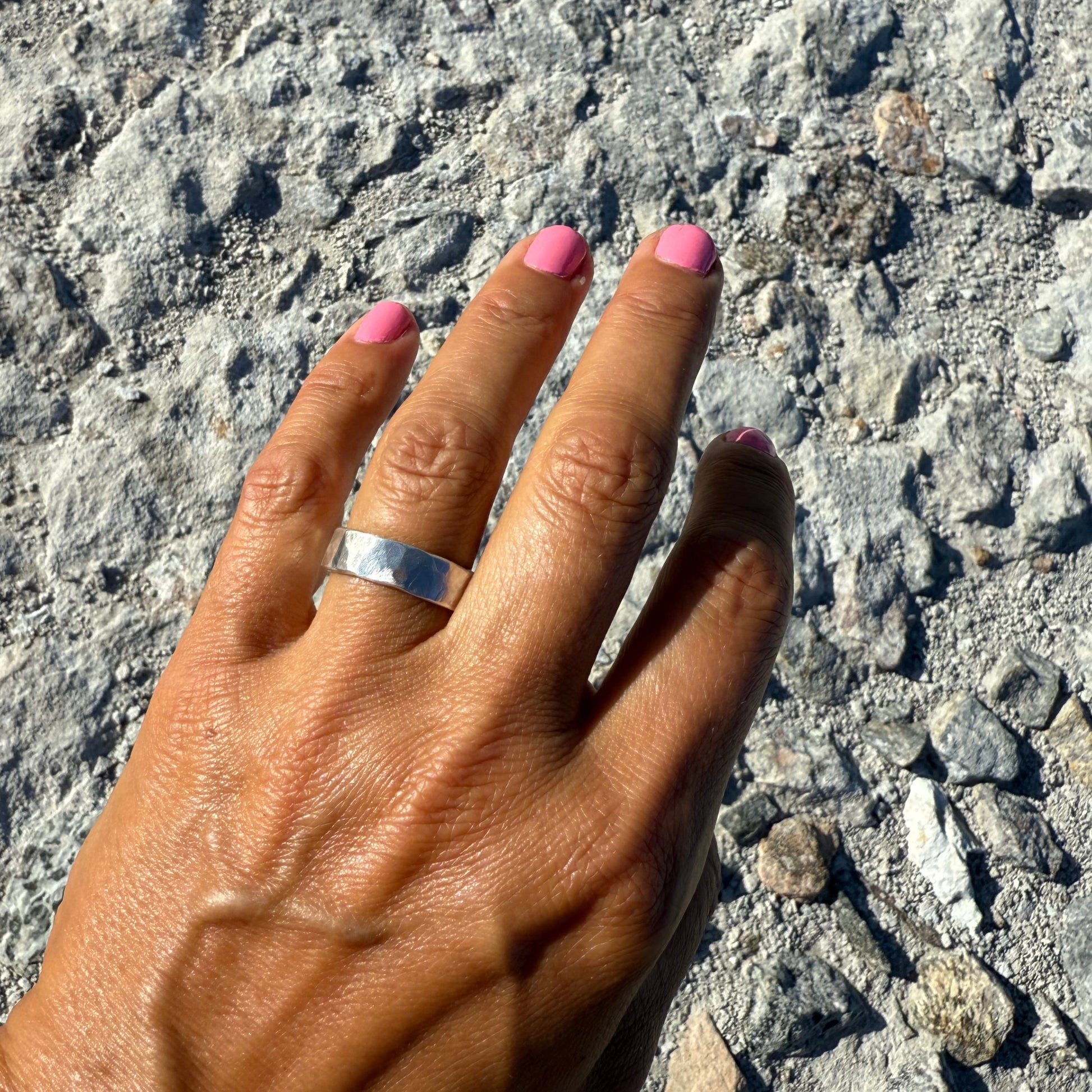 Hand with a sterling silver ring on a textured surface