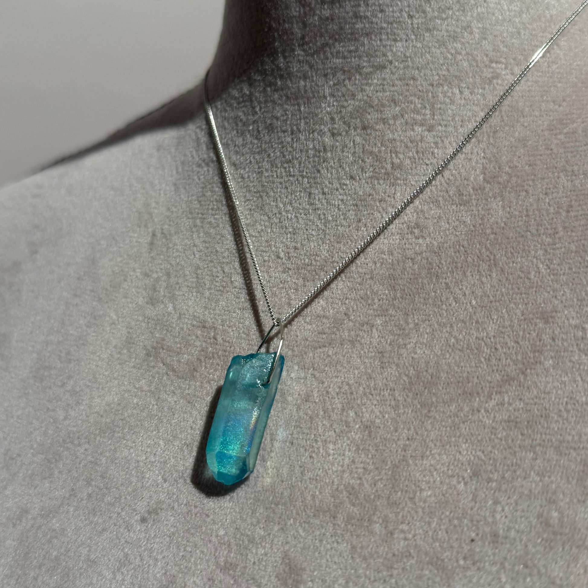 Necklace with a blue crystal pendant on a mannequin.