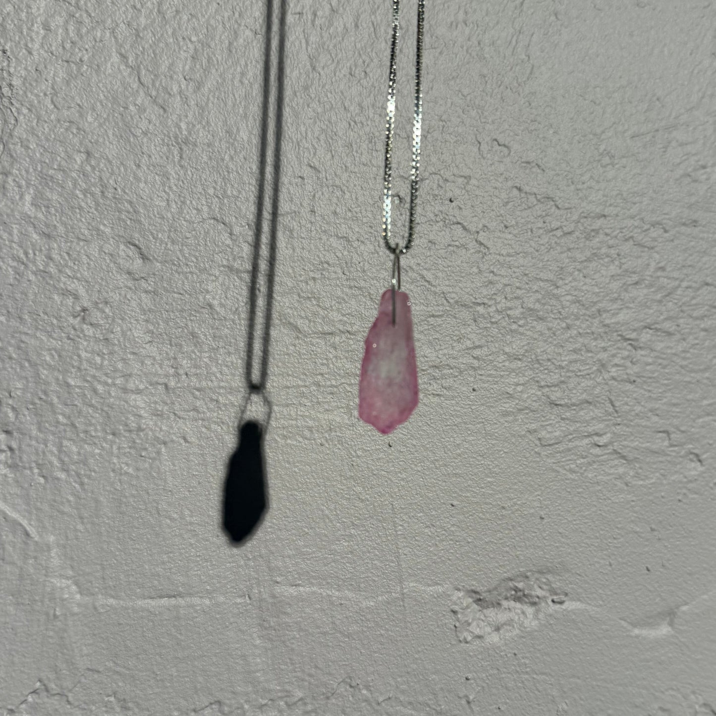 Small pink crystal on a venezia silver chain against a textured white wall