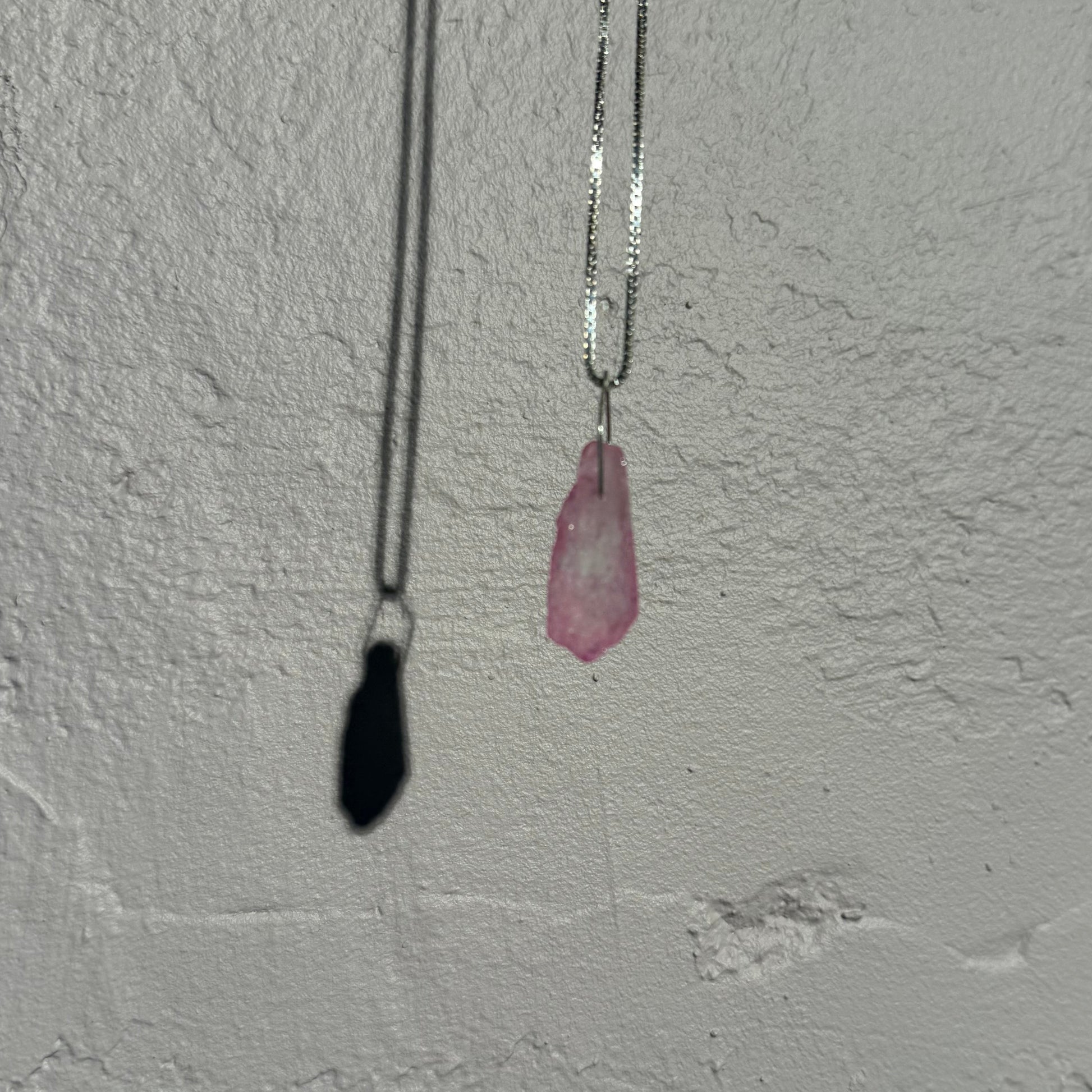 Small pink crystal on a venezia silver chain against a textured white wall