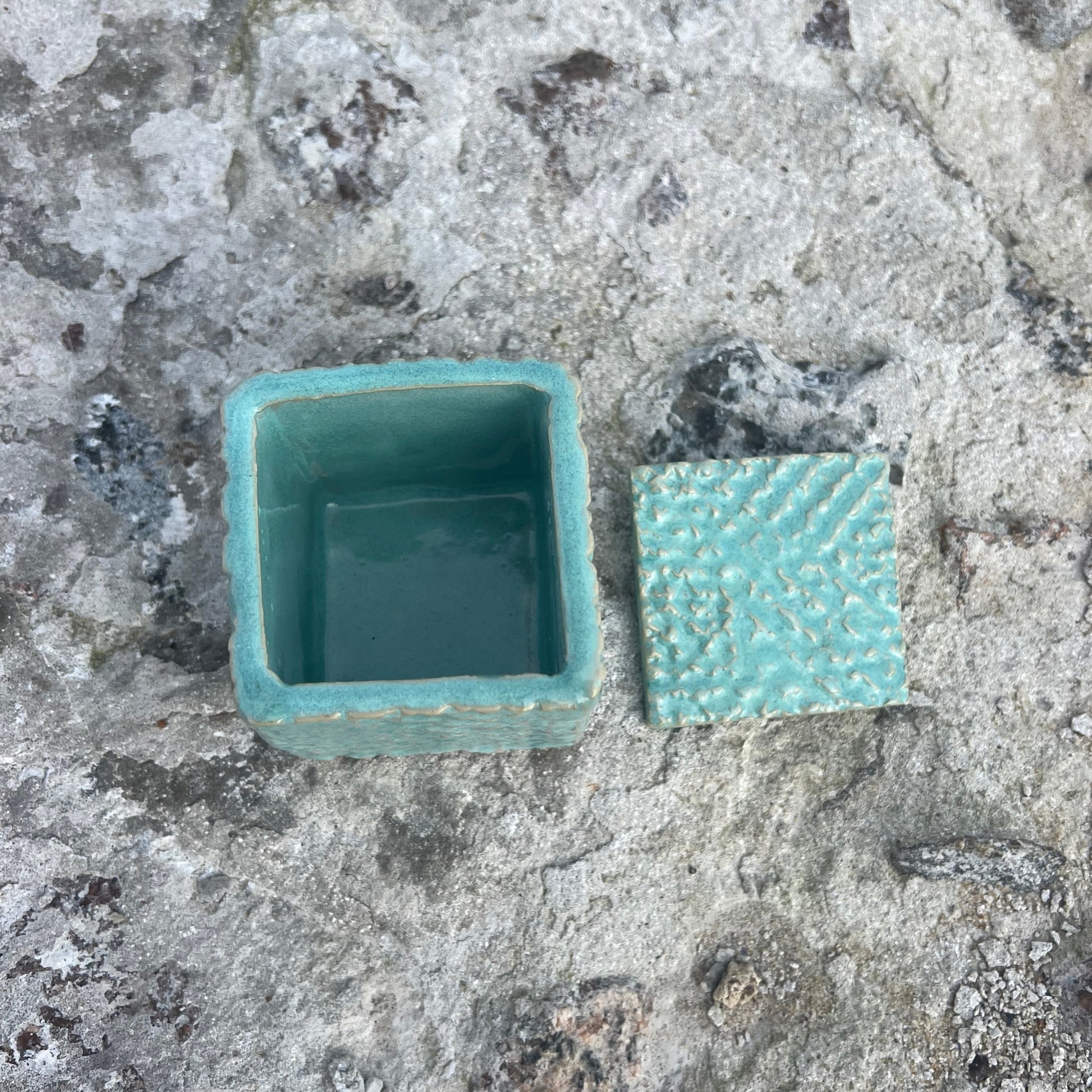 turquoise ceramic container on a textured stone surface
