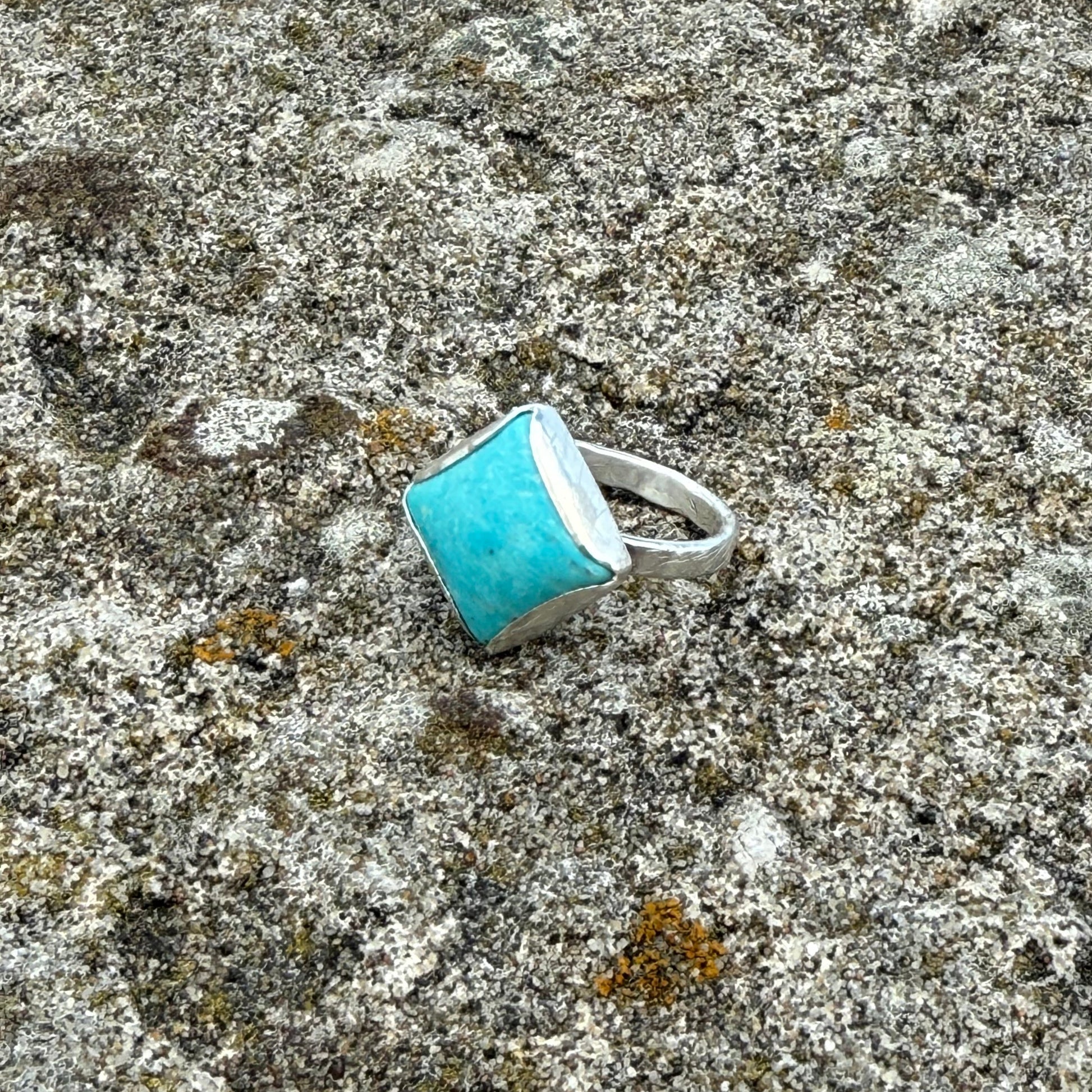 sterling silver ring with a square cabochon cut turquoise gemstone on a textured surface