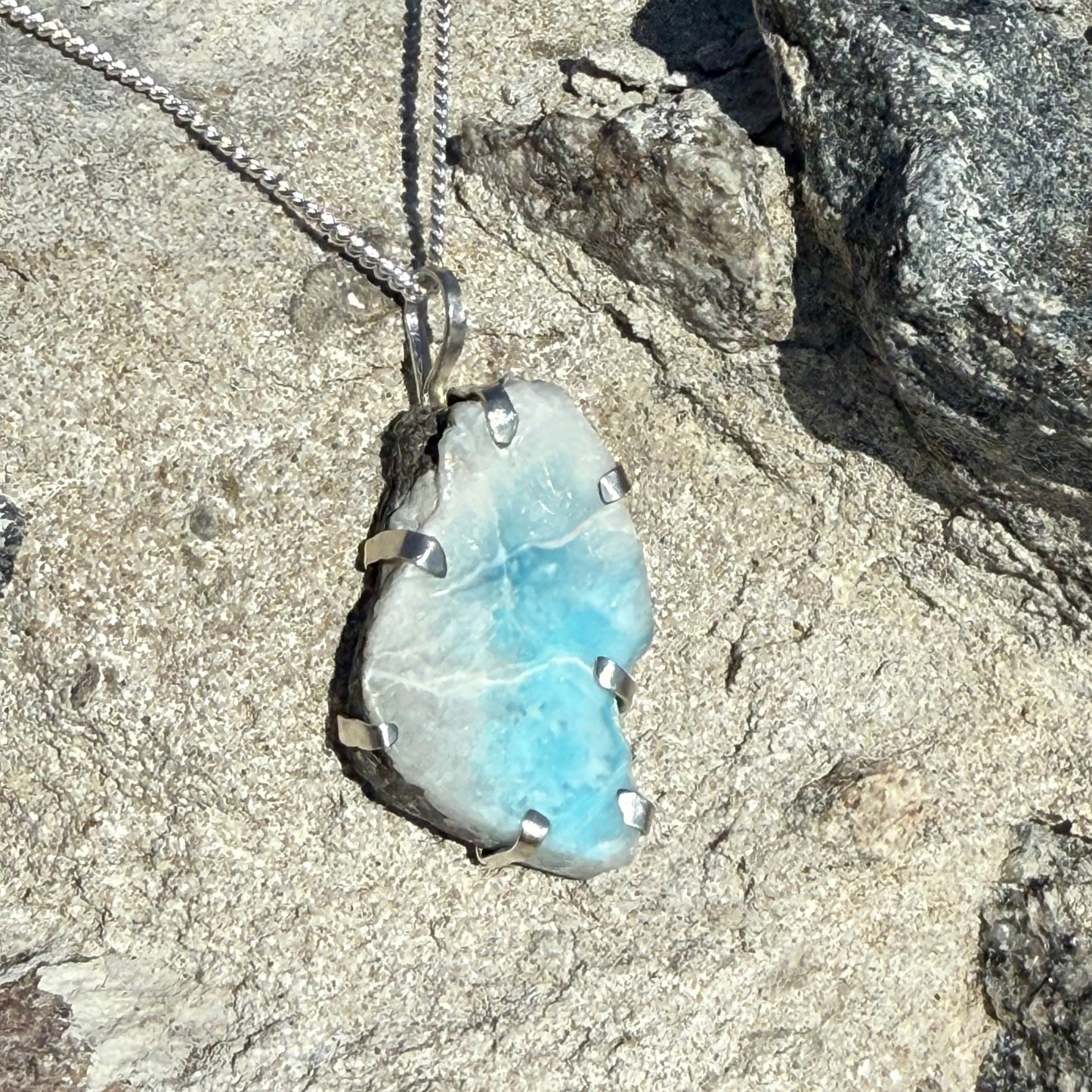 Necklace with a Larimar crystal pendant on a rocky surface