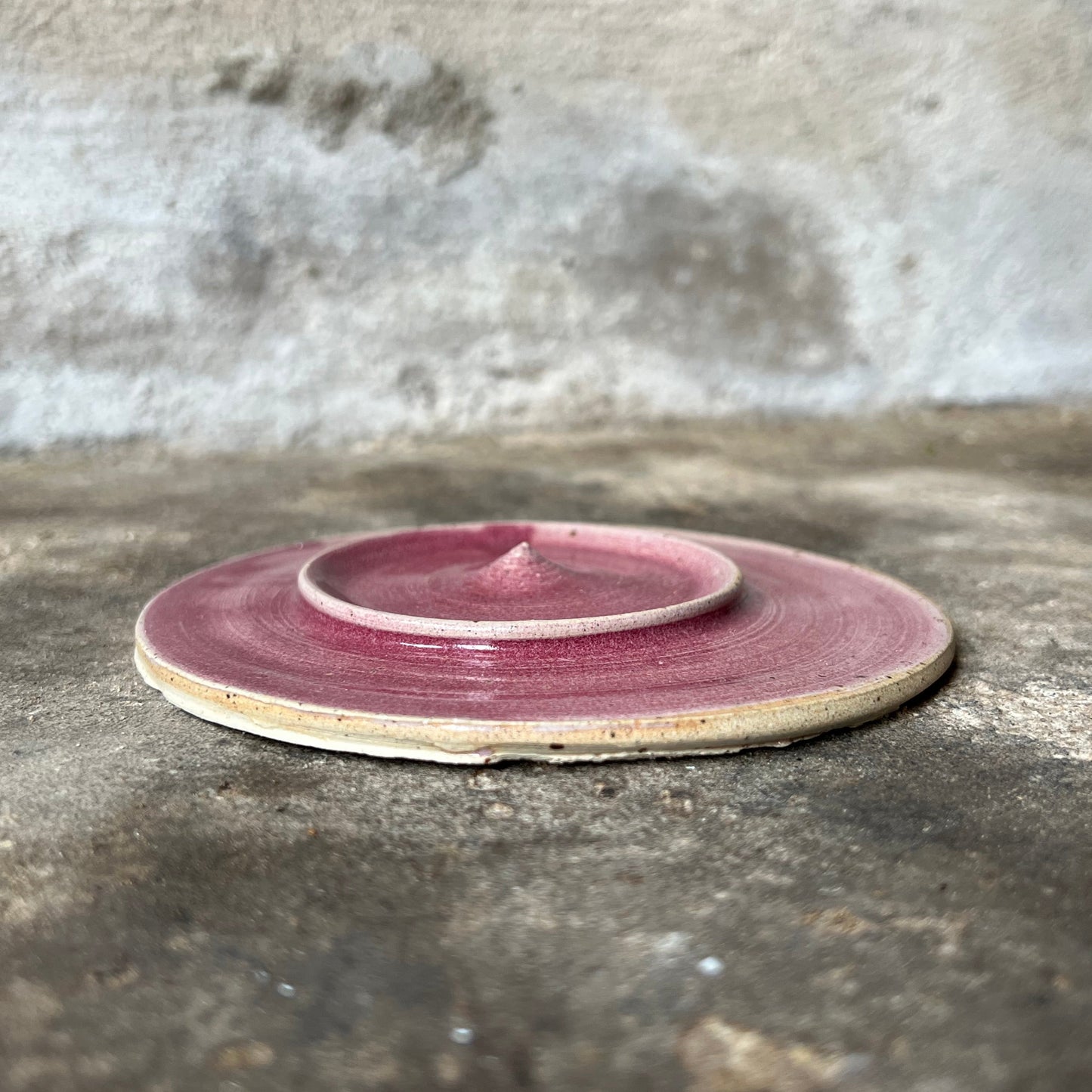 Pink ceramic jewelry plate on a textured stone surface