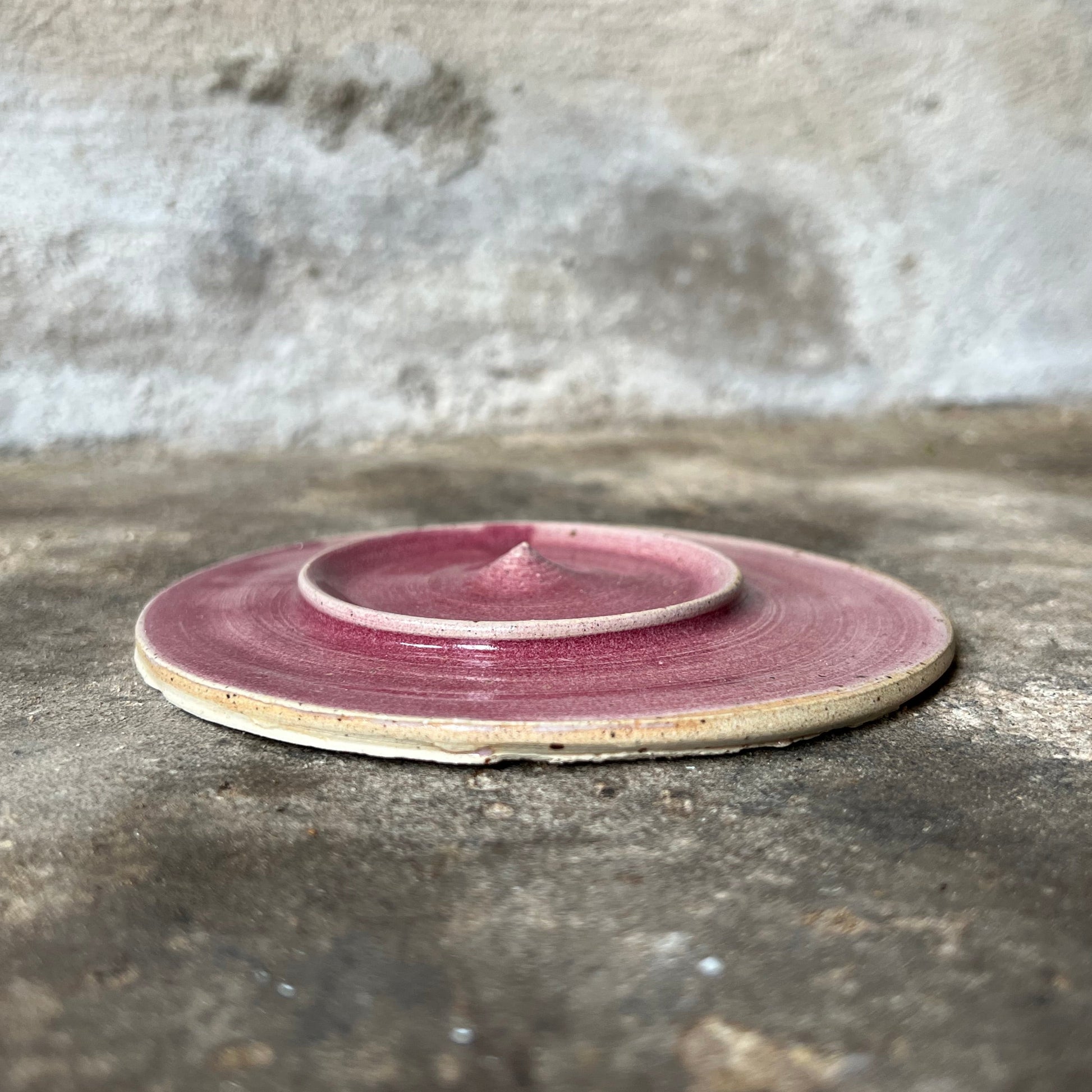 Pink ceramic jewelry plate on a textured stone surface