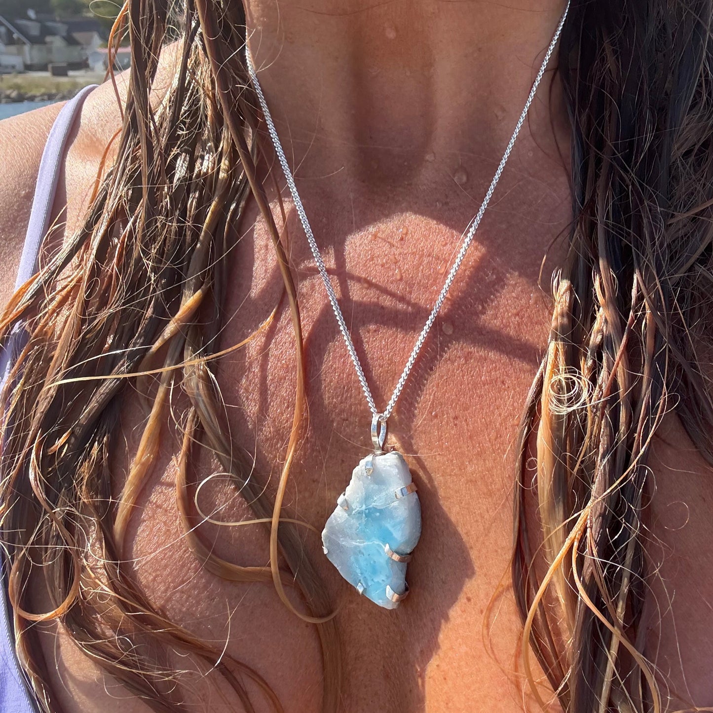 Close-up of a larimar silver necklace pendant on a person's chest.