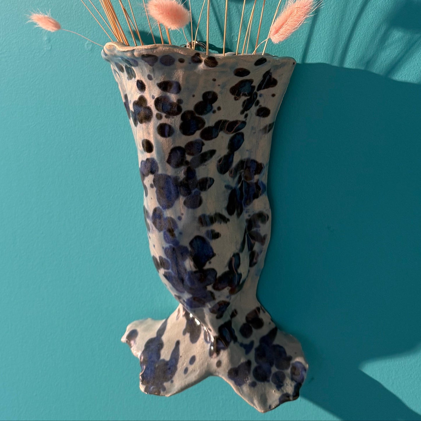 wall vase in the shape of a mermaid tale on a turquoise background