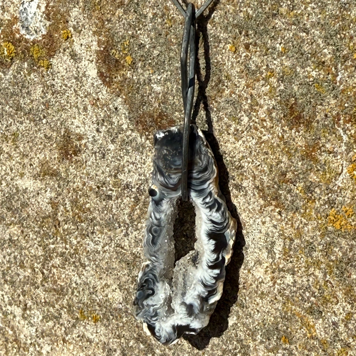oxidized dangly silver earring with black agate on textured stone surface
