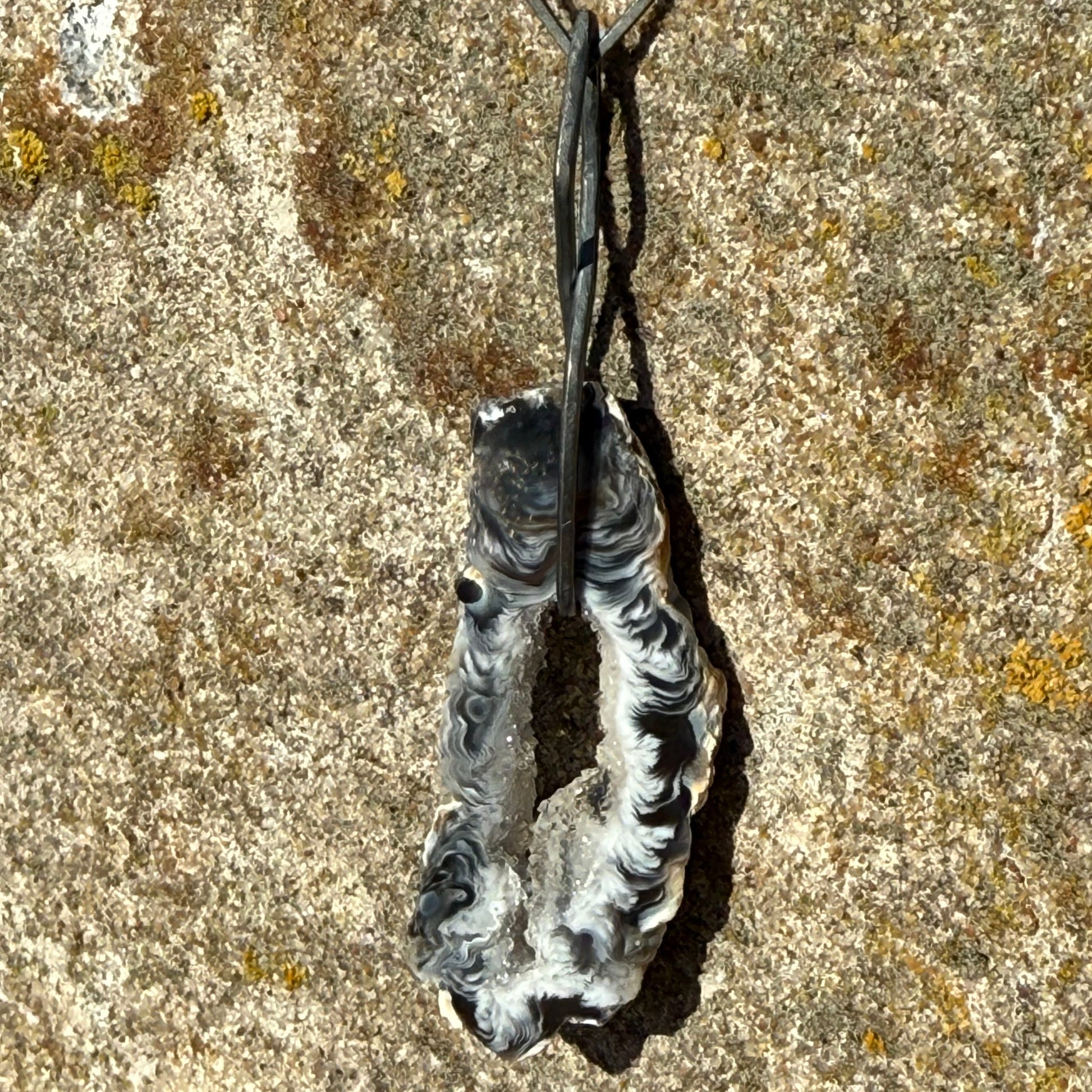 oxidized dangly silver earring with black agate on textured stone surface