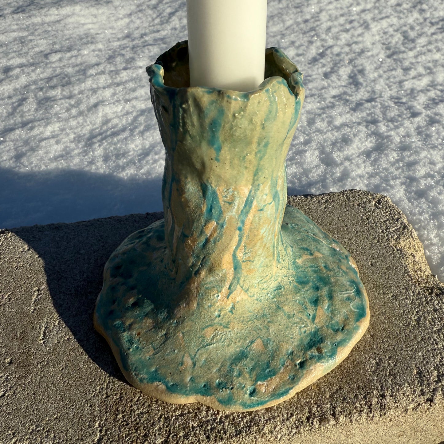 Ceramic candle holder with a textured surface on a sandy background