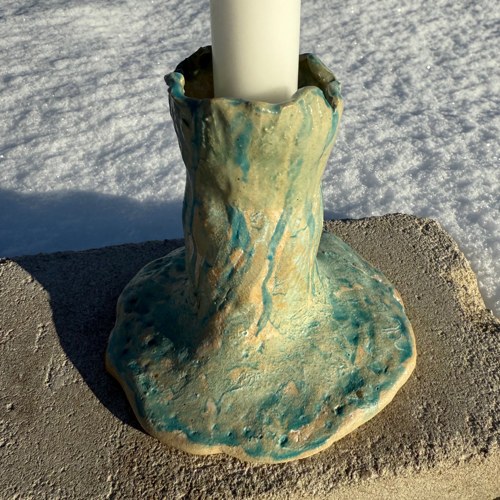 Ceramic candle holder with a textured surface on a sandy background