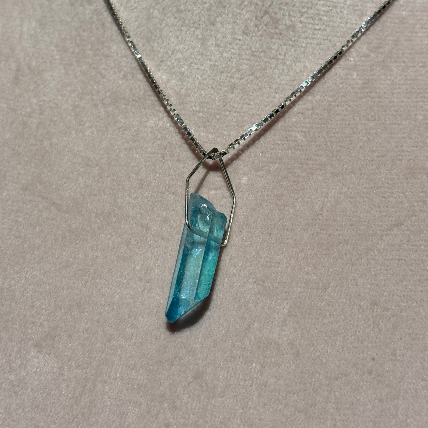 Necklace with a blue crystal pendant on a neutral background