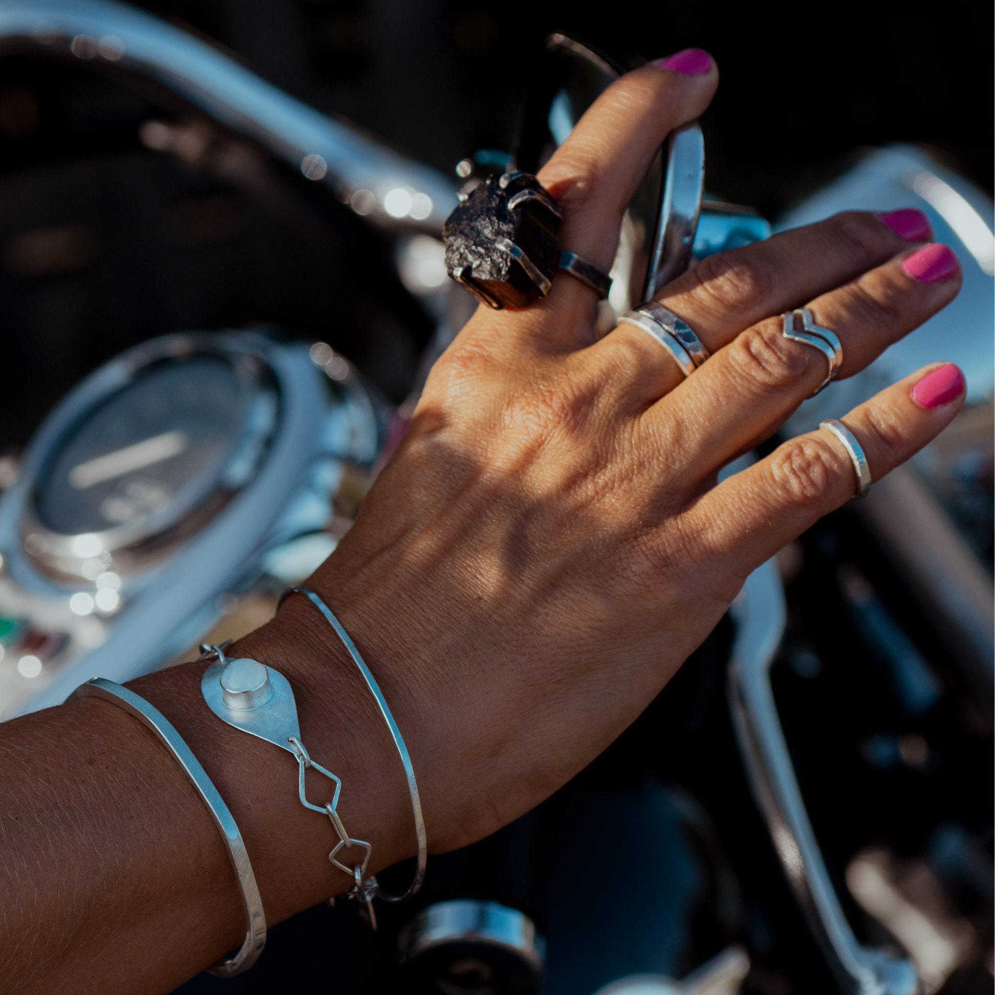 Hand with atelier Desirée handmade jewelry on a Kawasaki motorcycle handlebar