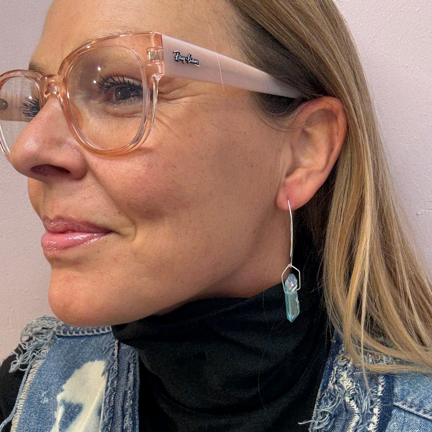 Pair of aqua blue titanium quartz dangling silver earrings on a woman with pink glasses.