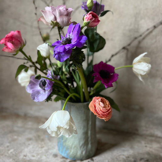 Vase with colorful flowers on a textured surface