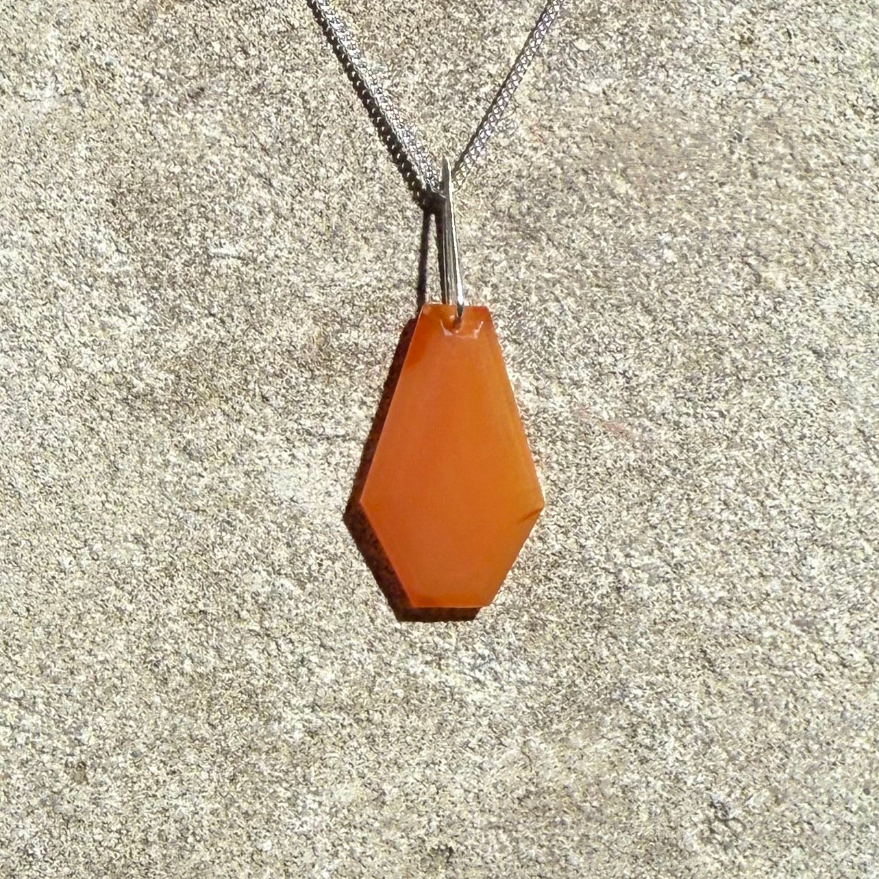 Sardonyx crystal silver necklace on a textured surface 