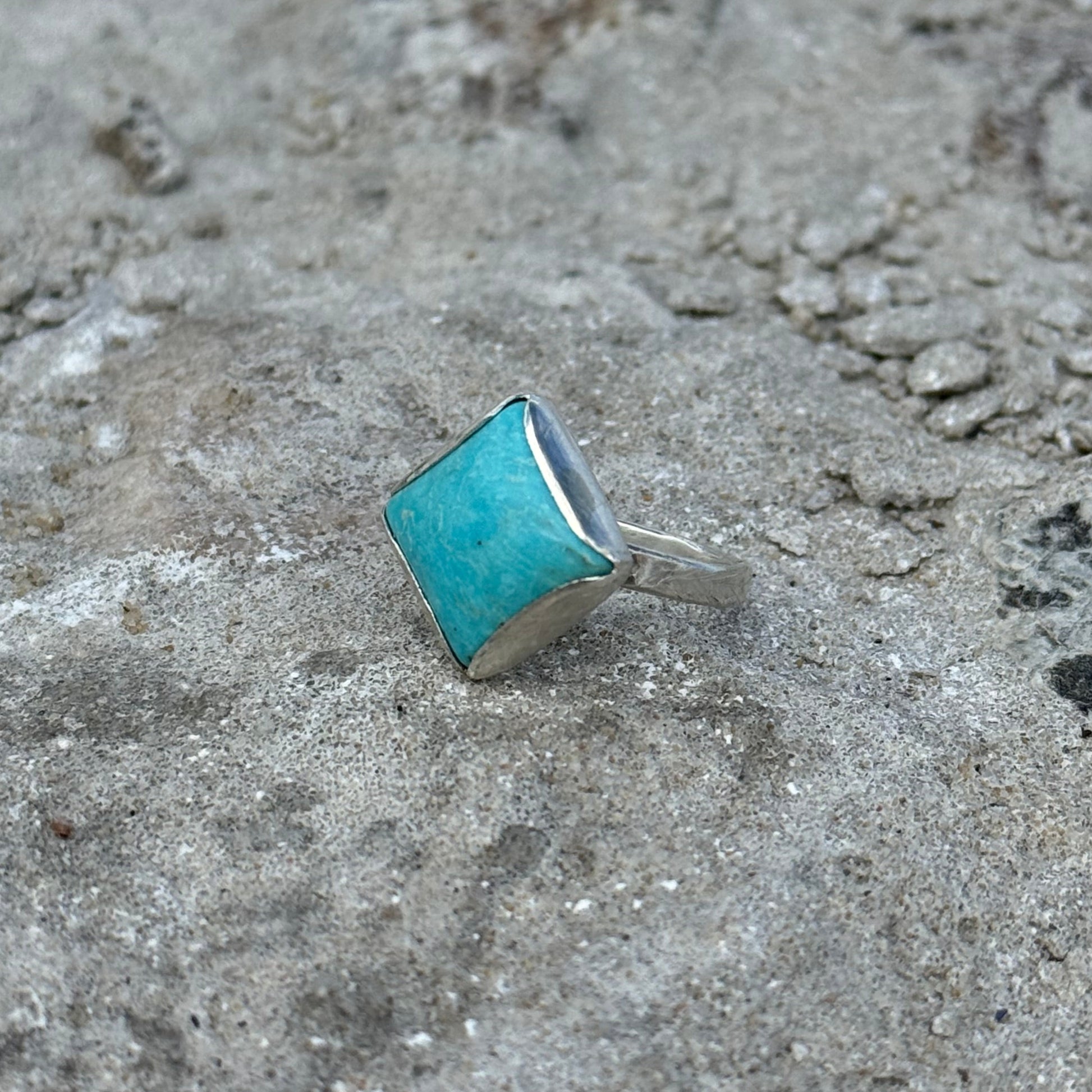 Small turquoise square ring on a textured gray surface