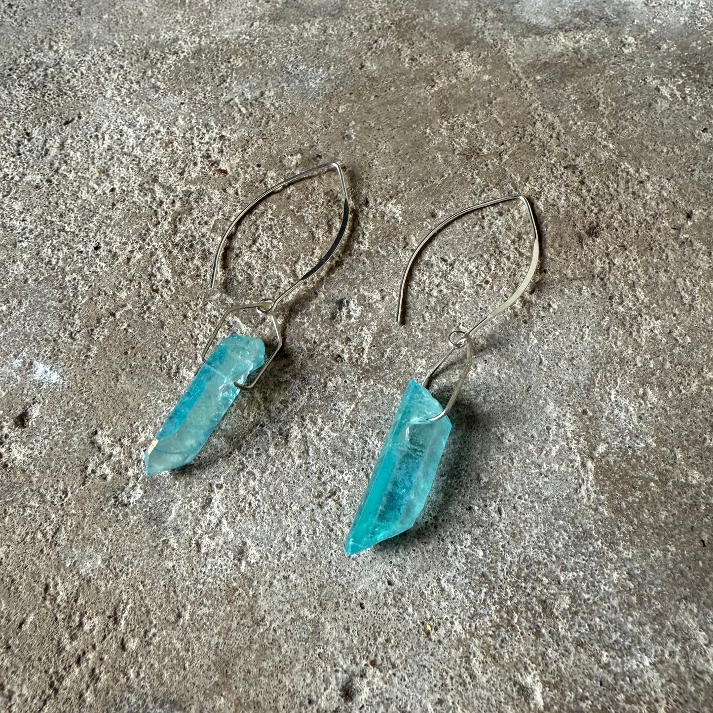 Blue crystal earrings on a textured surface
